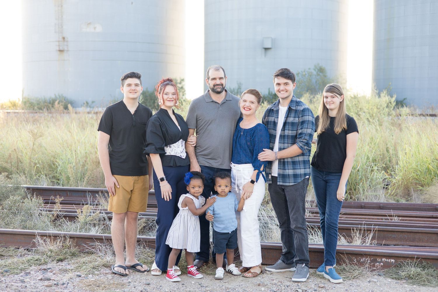 Family of 8 stands in front of Prosper Silos for first family photo as a family of 8 after adoption captured by McKinney Family Photographer