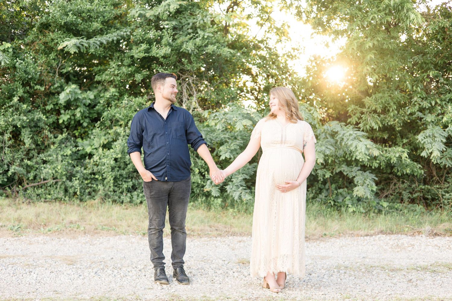 expecting mom and dad pose hand in hand during golden hour maternity session at erwin park in mckinney texas with dfw family photographer