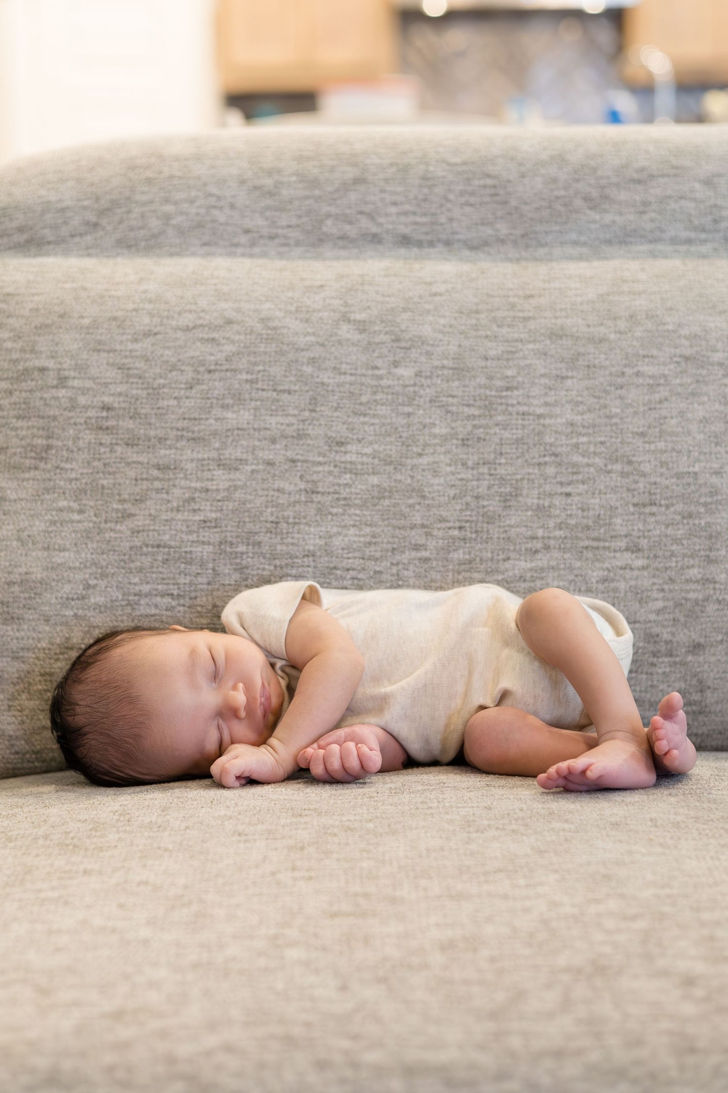 Newborn baby boy lays on couch during lifestyle newborn session with Reagan Marie Photography in McKinney, TX