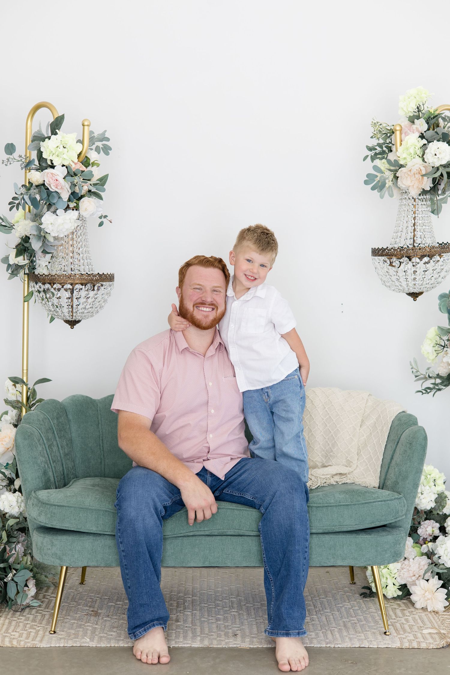 Dad and son pose together on green couch in studio with Newborn photographer Reagan Marie Photography