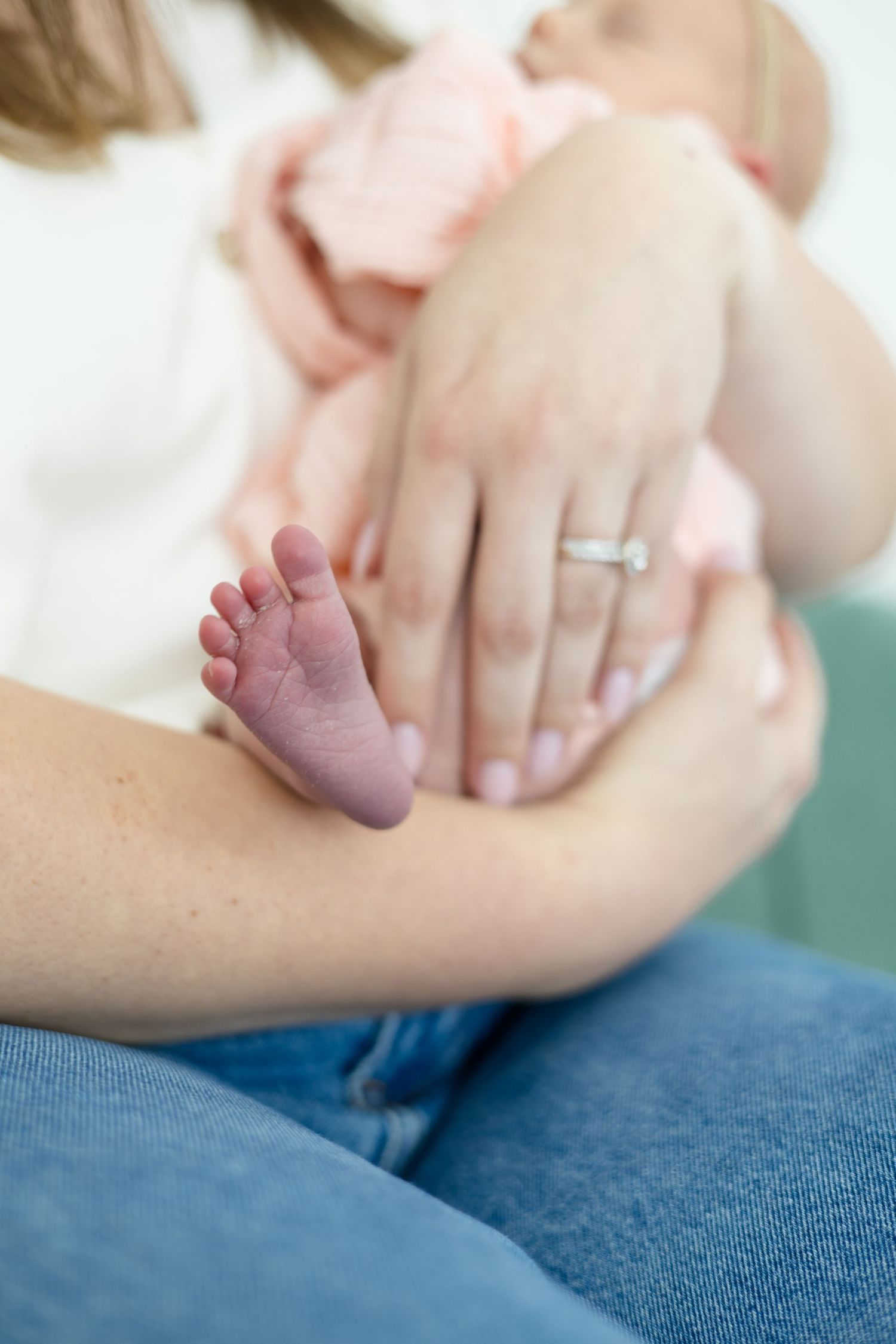McKinney newborn photographer captures detailed shot of mom and newborn baby girl focusing on mom's hand and baby's foot