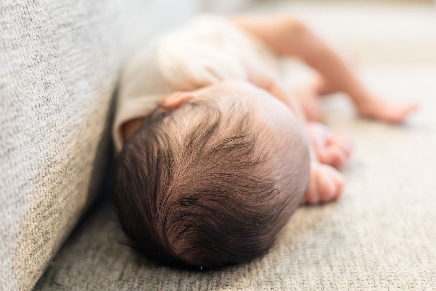 Newborn baby boy lays on couch during lifestyle newborn session with Reagan Marie Photography in McKinney, TX