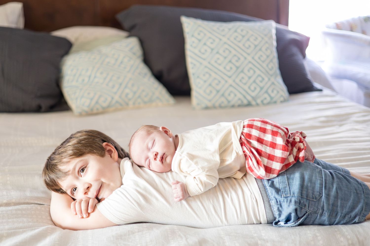 Newborn baby girl lays on back of older brother during lifestyle newborn session with McKinney family photographer Reagan Marie Photography