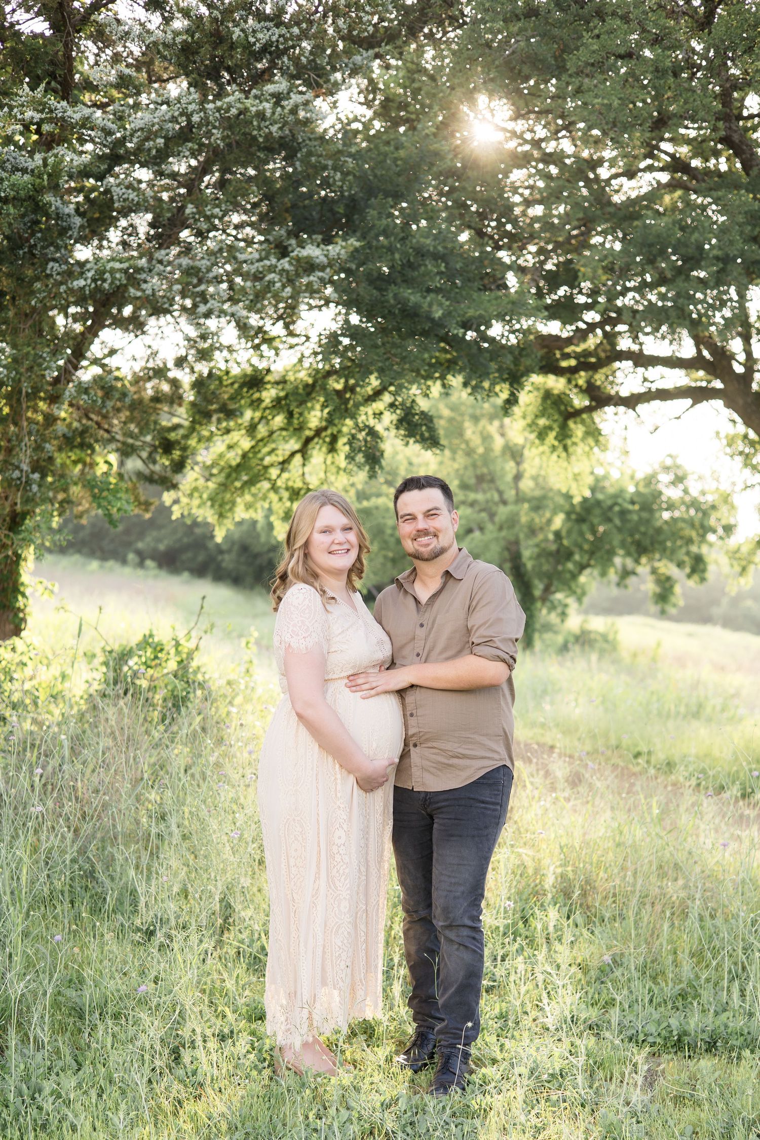 expecting mom and dad pose under trees during golden hour at erwin park in mckinney texas with dfw maternity photographer