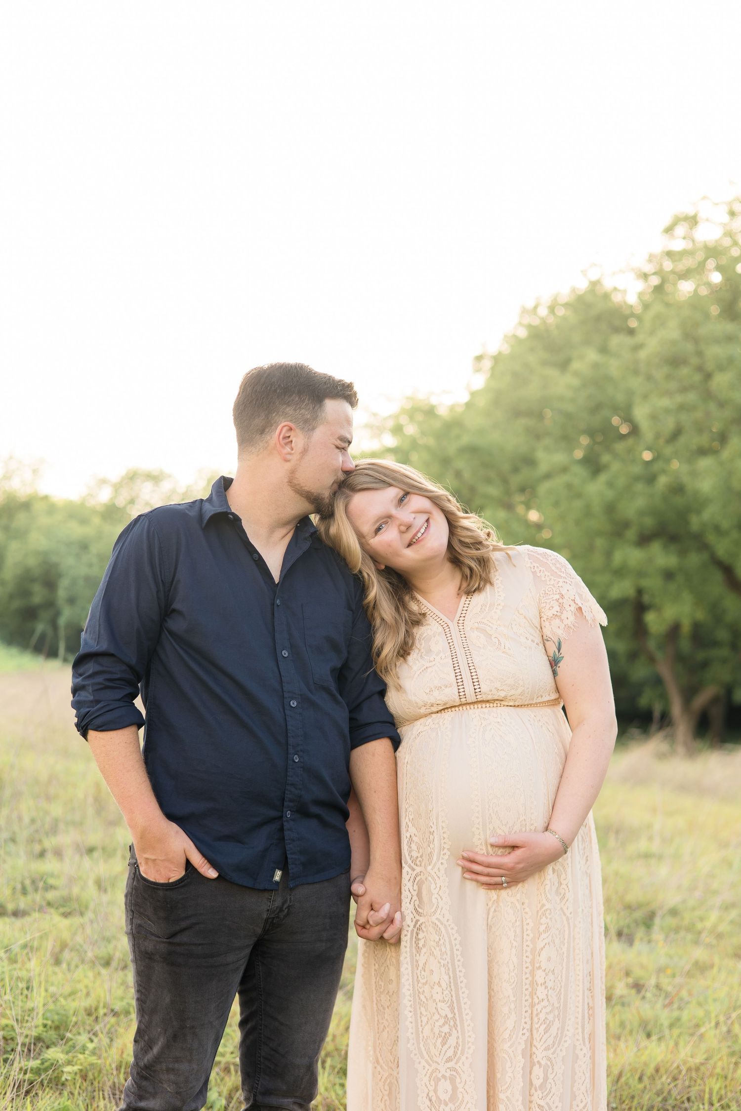 Dad kisses mom on the head during mckinney maternity session with mckinney maternity photographer at Erwin Park