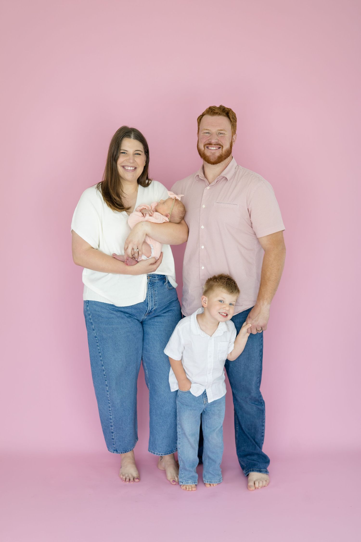 Family of 4 poses together during lifestyle newborn session in the studio with family photographe Reagan Marie Photography