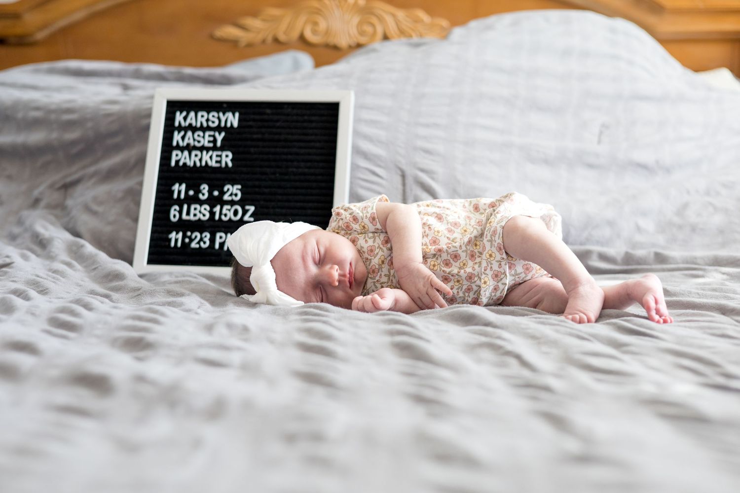 Baby girl lays on parents bed during in-home lifestyle newborn session with McKinney Newborn Photographer, Reagan Marie Photography