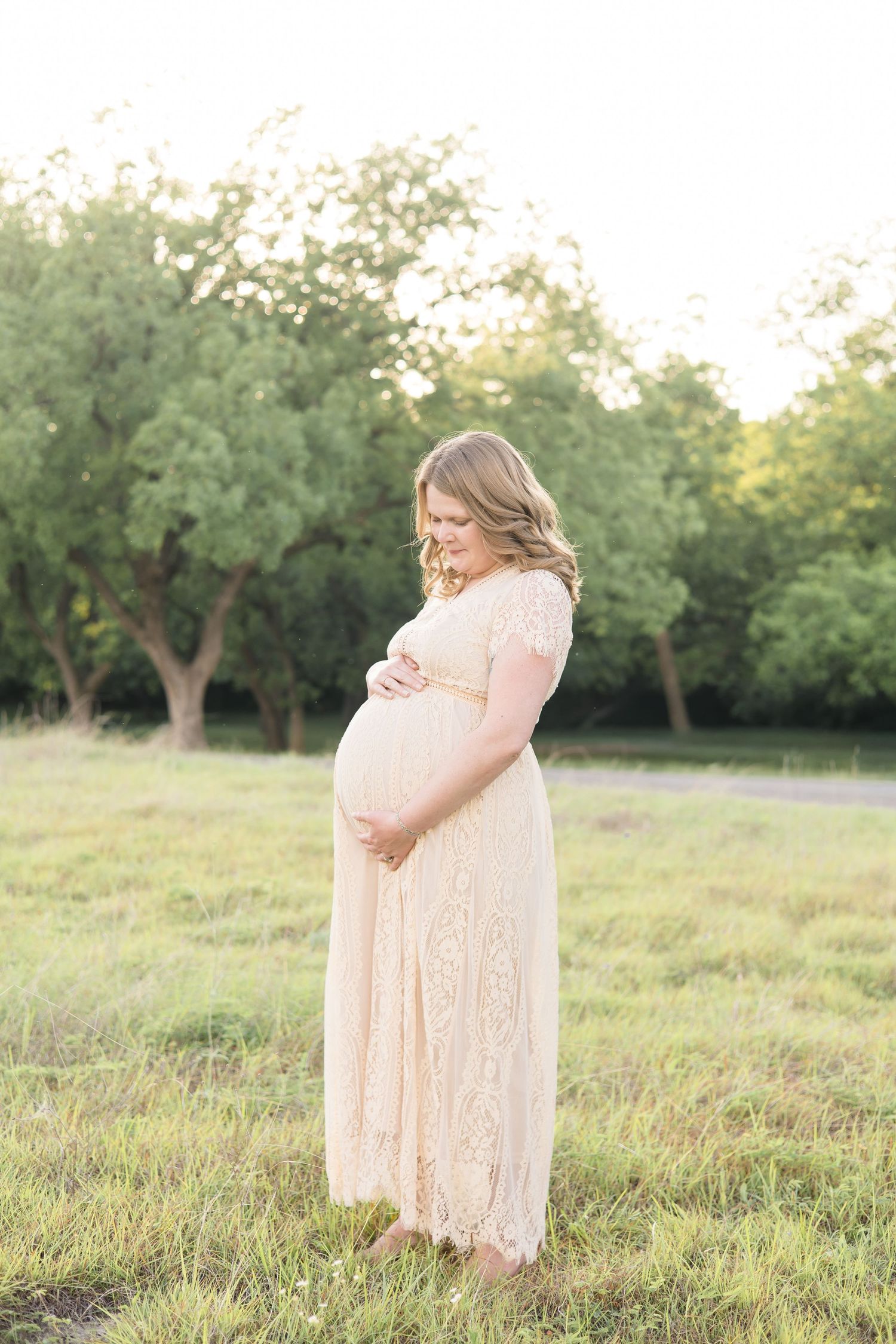 mom poses with hands on pregnant belly during maternity portrait session at erwin park in mckinney texas with mckinney based photographer