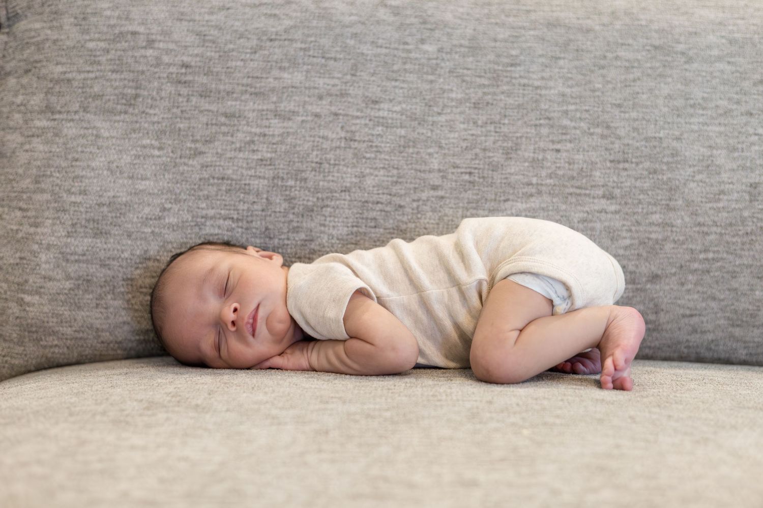Newborn baby boy lays on couch during lifestyle newborn session with Reagan Marie Photography in McKinney, TX