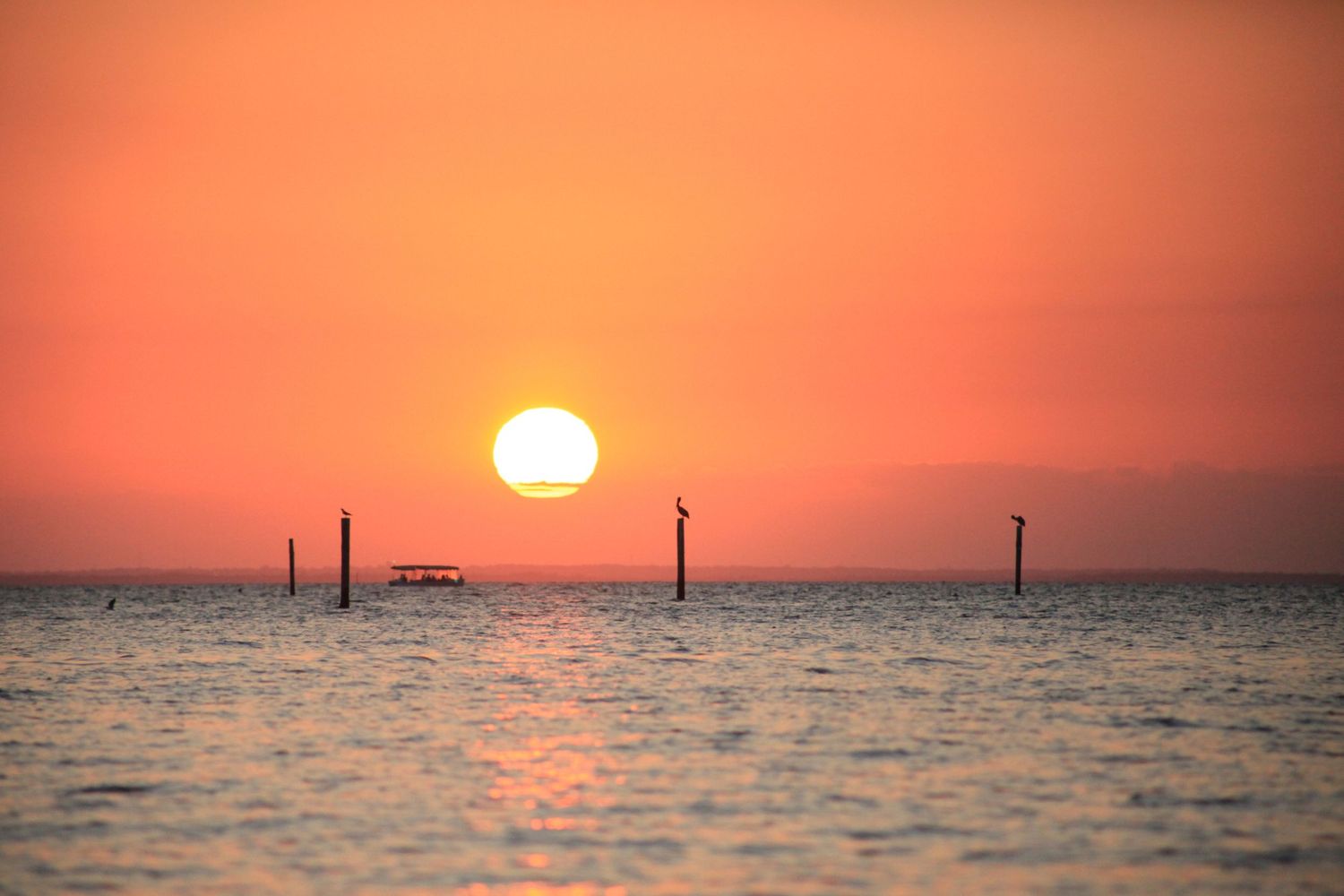 A sunset over the water with a boat in the distance