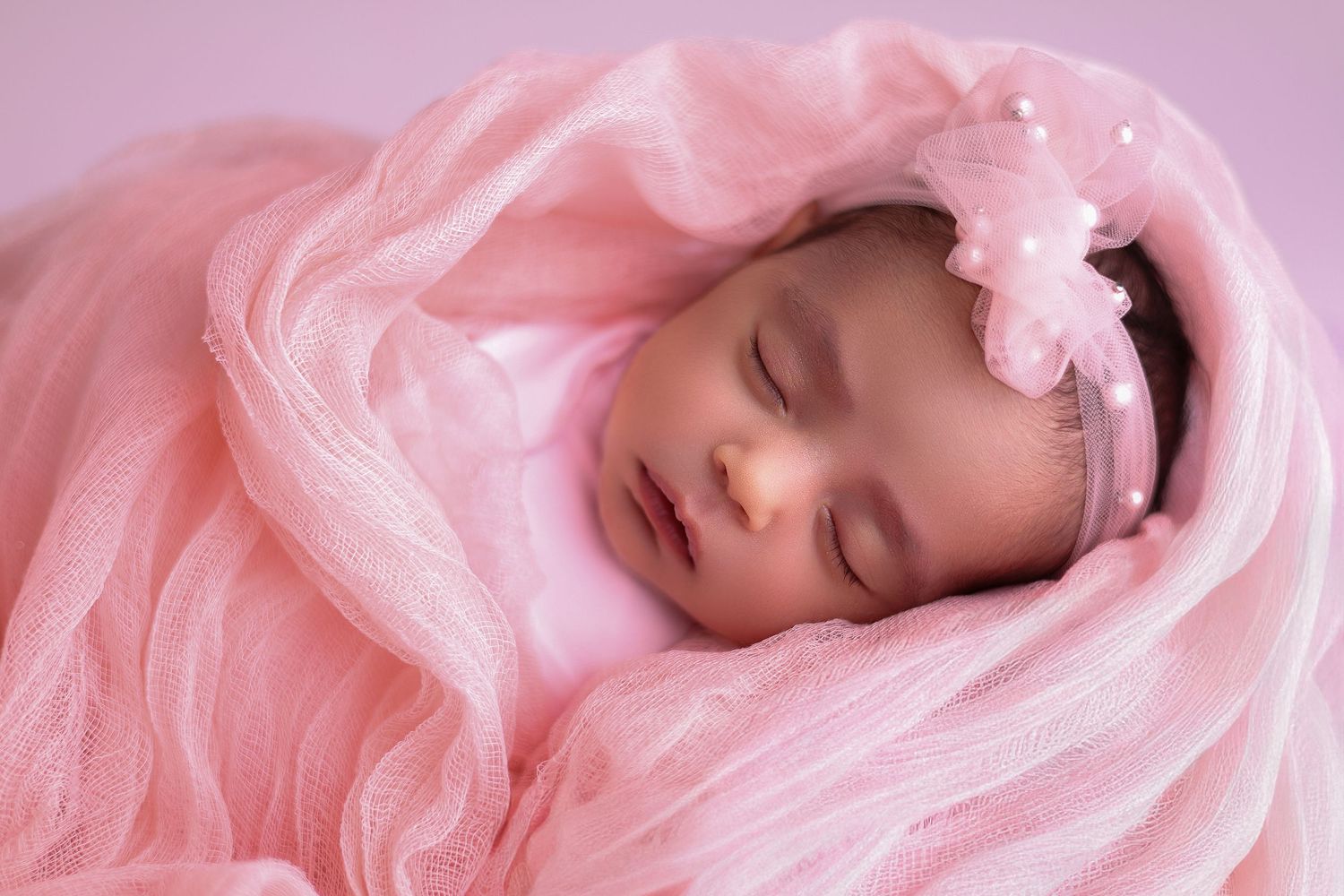 Artistic portrait series showing a person wrapped in soft pink fabric against a pink background.