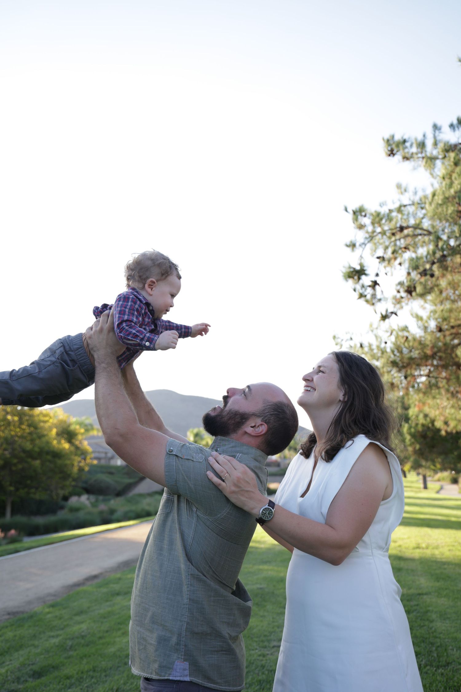 Family poses together on a grassy lawn during golden hour with mountains in the background.