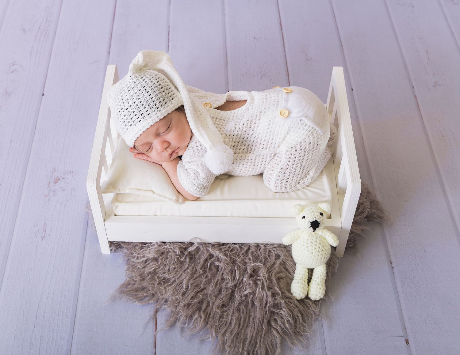 A cozy knit blanket with tasseled fringe is draped over a white bench with decorative pillows.