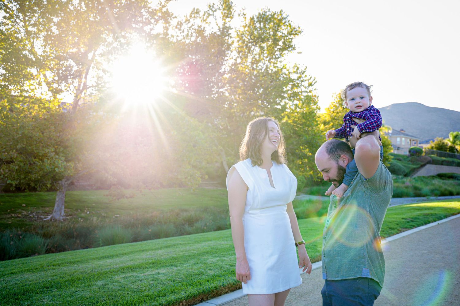 Family poses together on a grassy lawn during golden hour with mountains in the background.