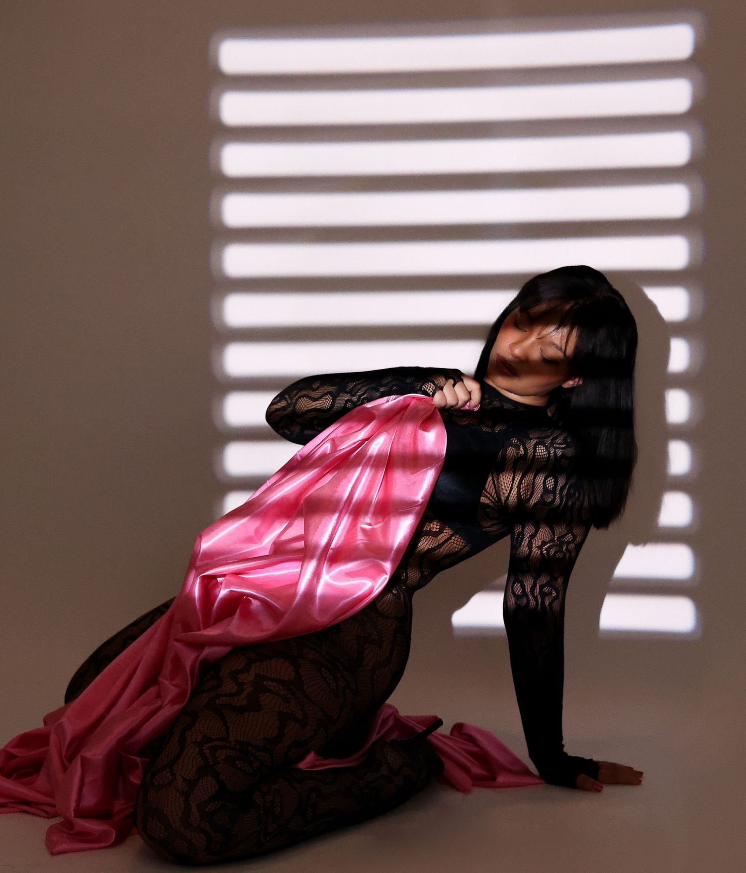 Artistic portrait series showing a figure in black dress reclining against pink fabric with dramatic window light and shadows.