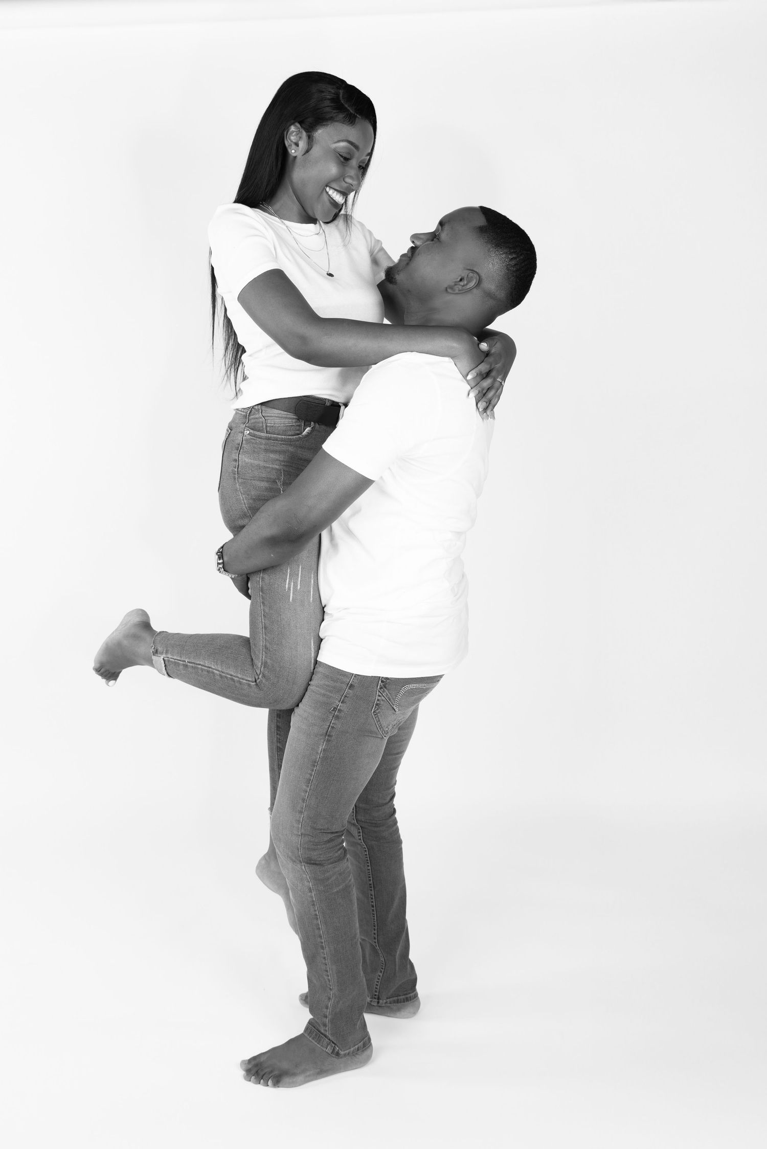 Black and white engagement photos showing couple in casual attire embracing in studio setting.