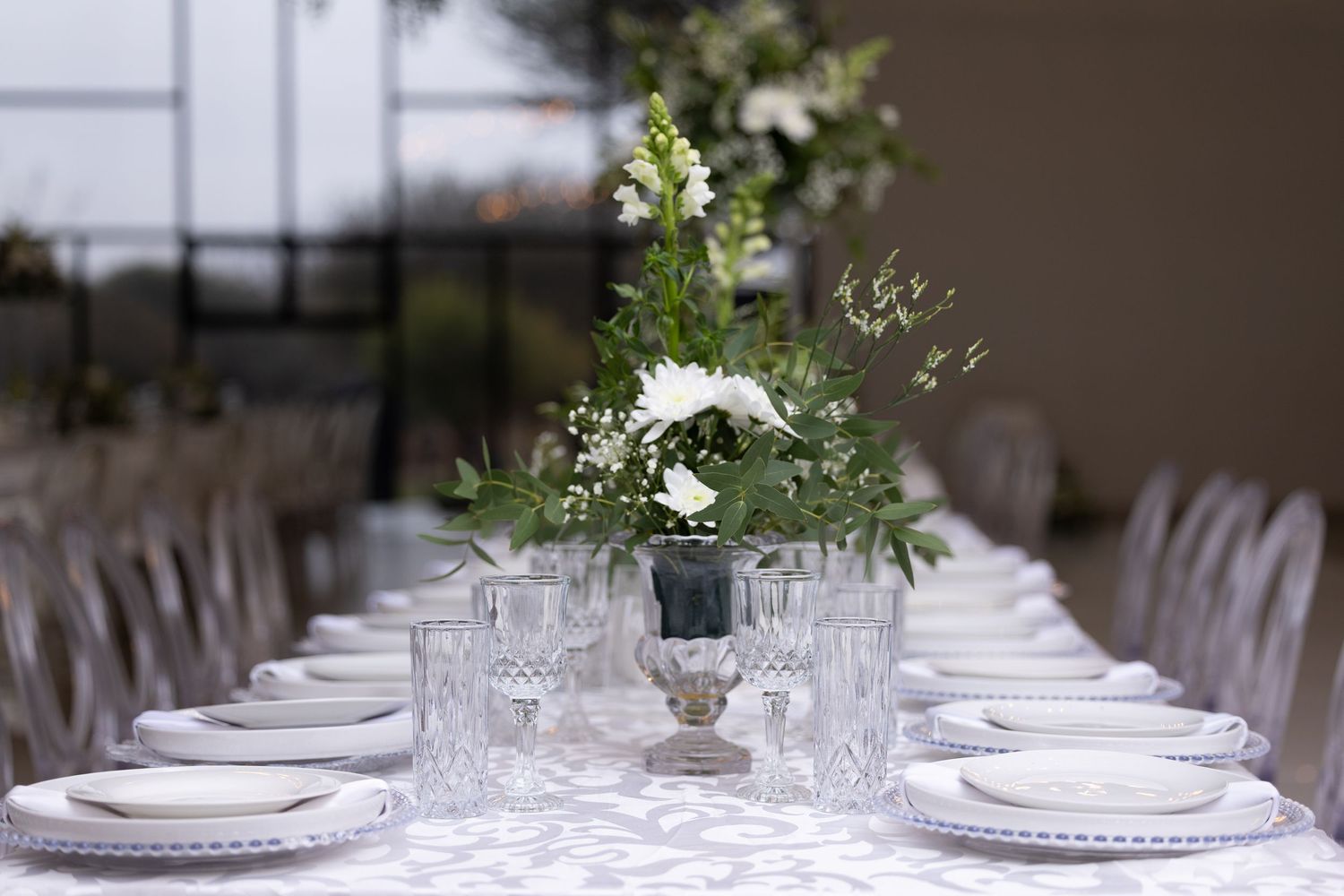 Elegant wedding reception table setting with white linens and floral centerpieces.