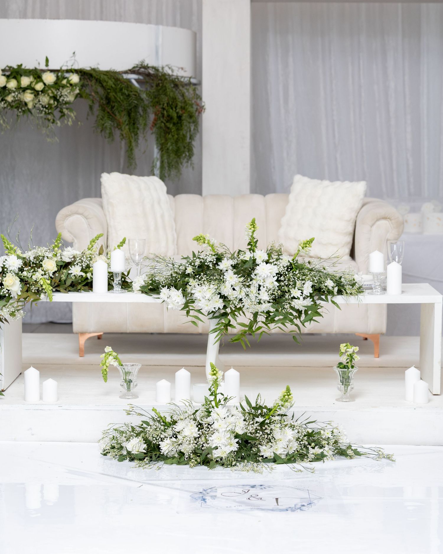 Elegant white wedding reception table with floral centerpieces and candles.