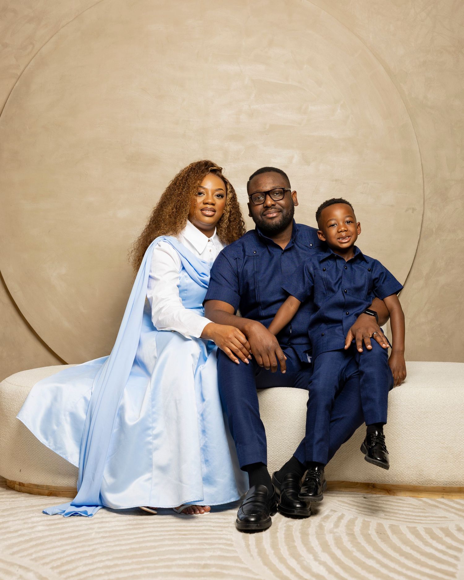 Family portrait featuring coordinated navy blue and white outfits against neutral backdrop.