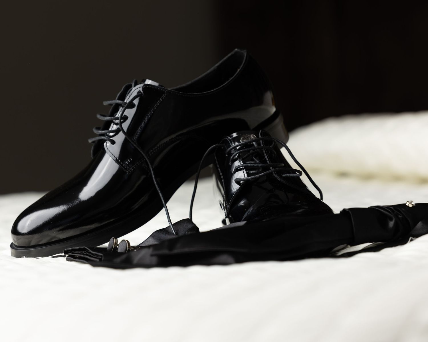 Row of black formal dress shoes lined up on white surface.