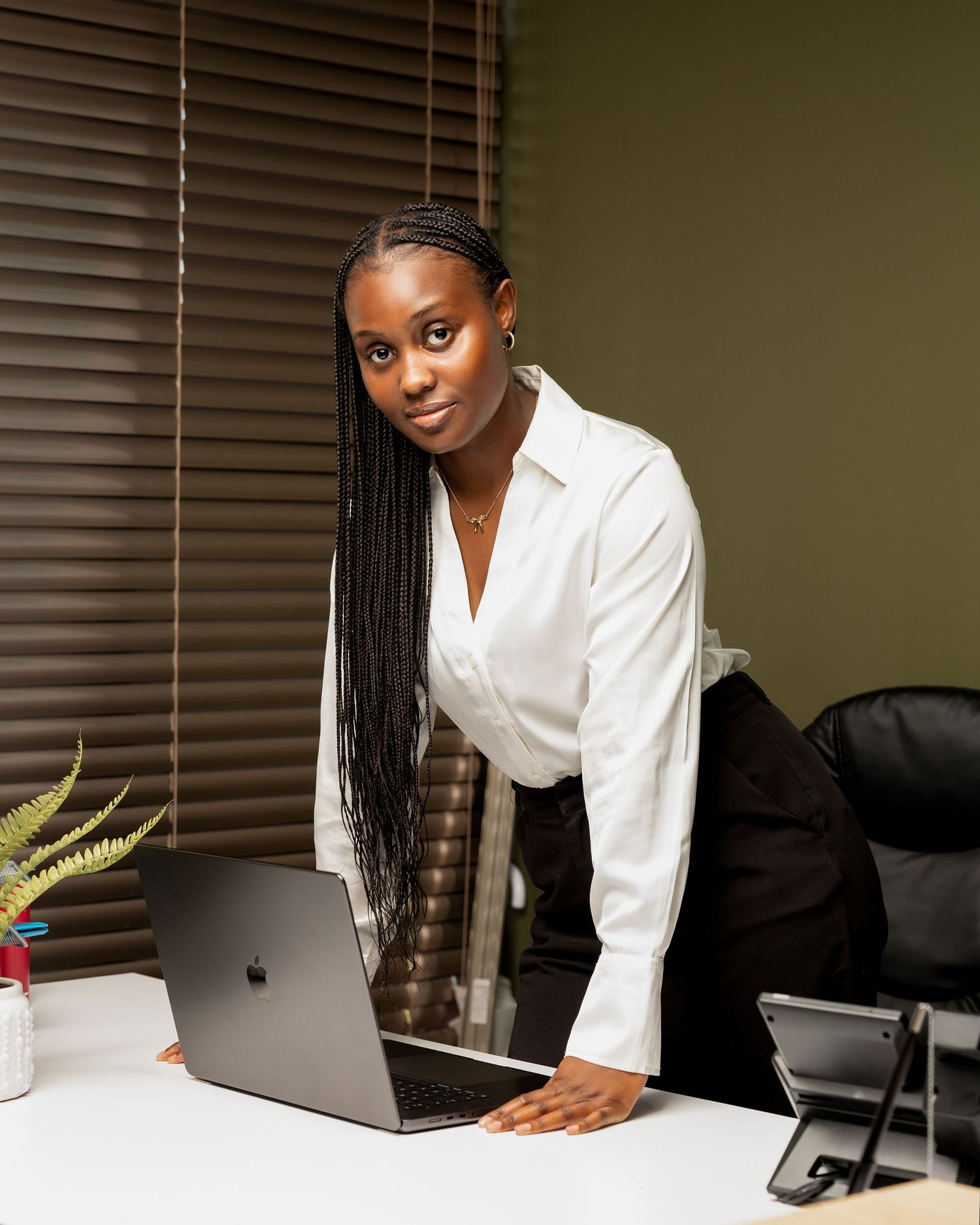 Professional working at a desk with laptop and plants in modern office setting.