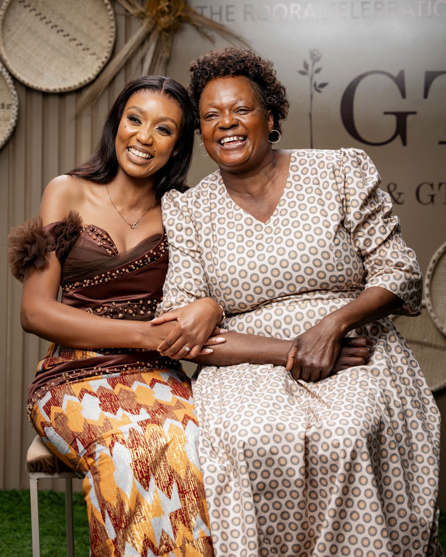 Two women smiling and posing together at a celebration event, wearing elegant traditional and formal attire.