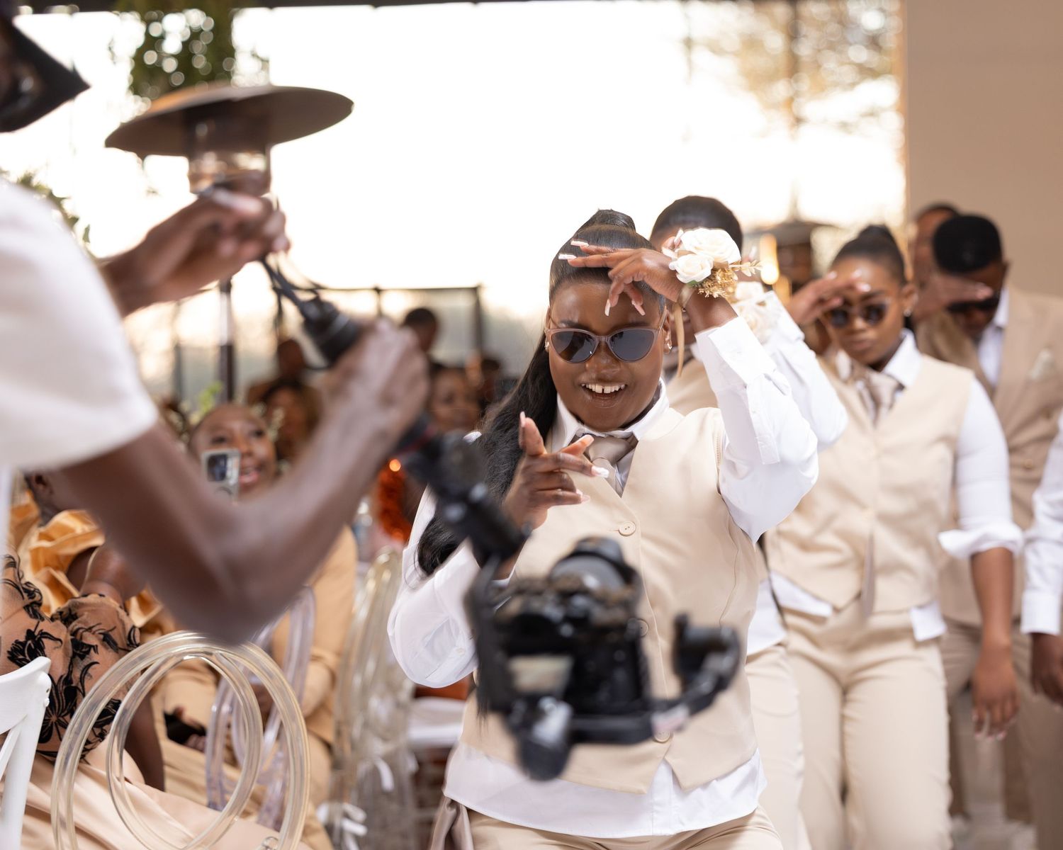 Wedding guests in cream-colored attire celebrating outdoors.