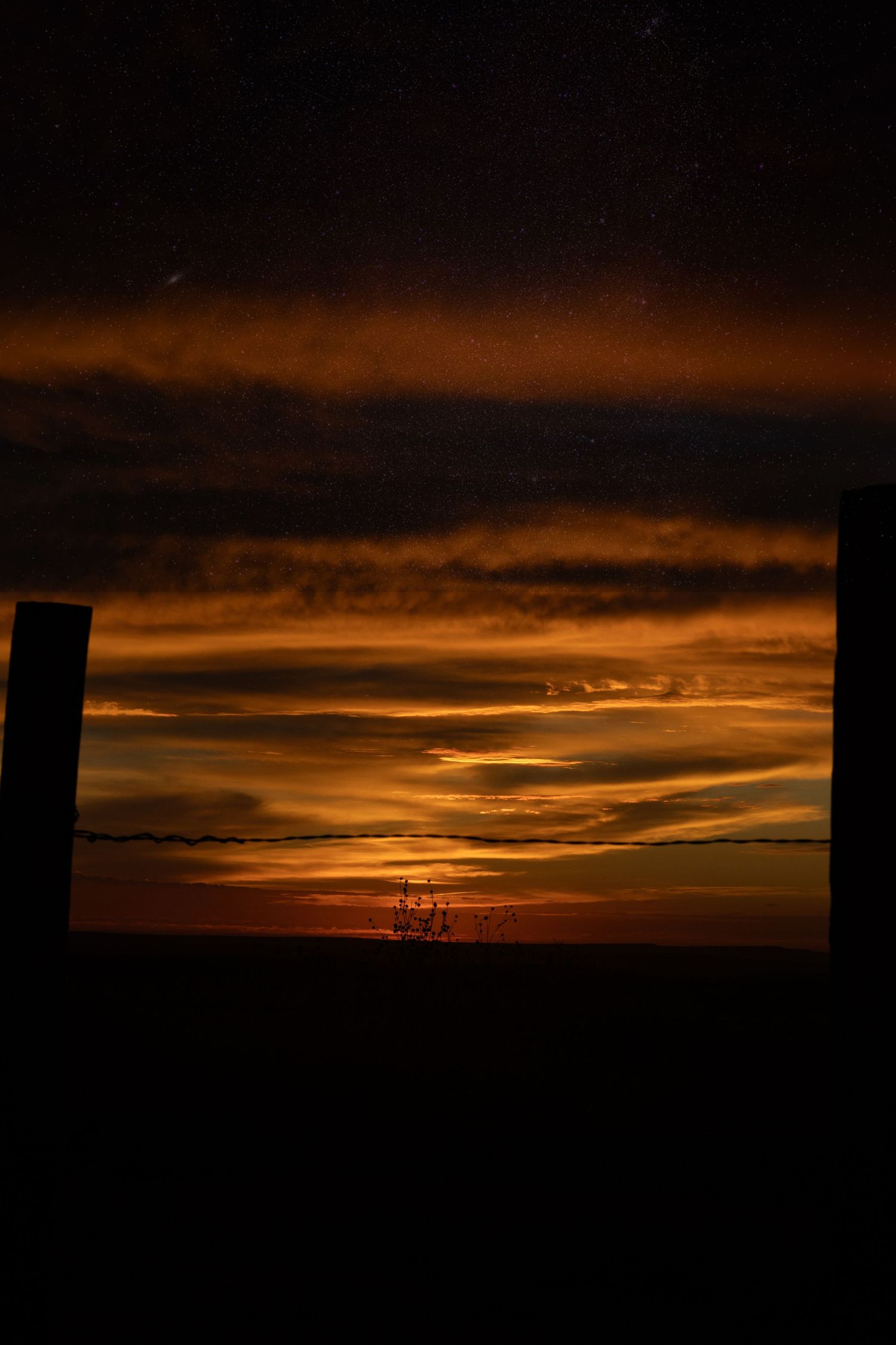 Dramatic orange and red sunset sky with dark clouds viewed through a framed outdoor opening.