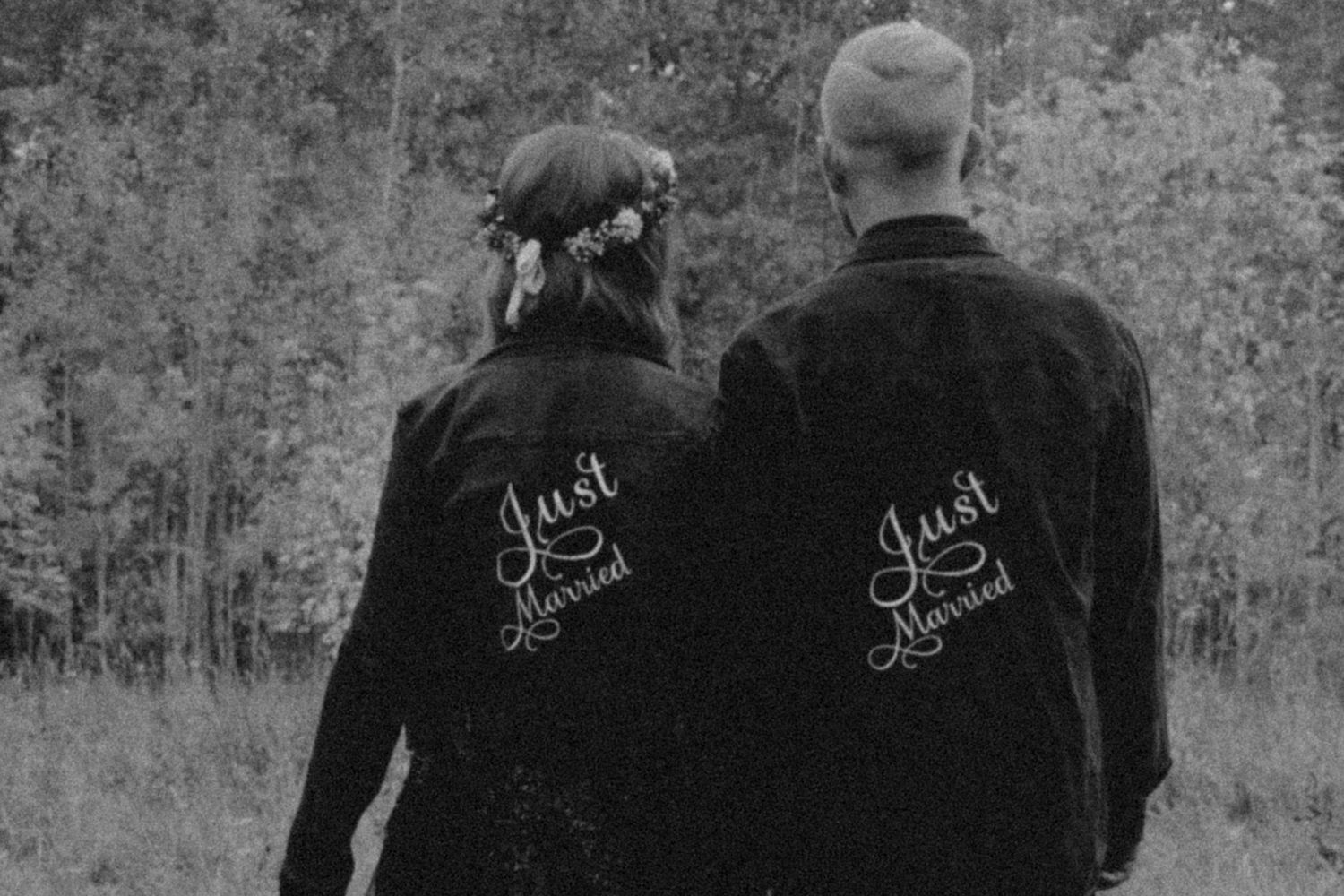 Newlywed couple wearing matching Just Married denim jackets stand in autumn forest setting in Winnipeg