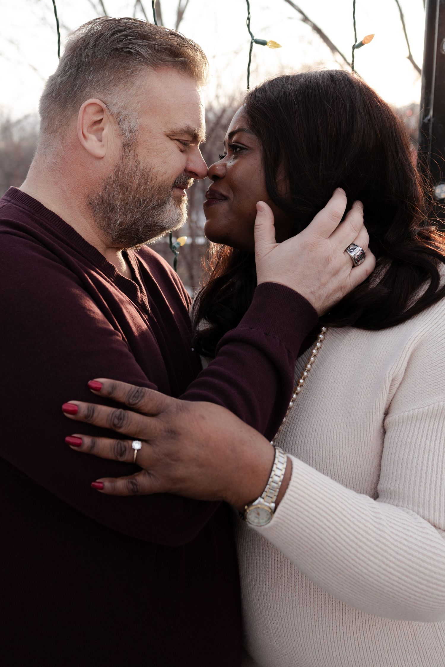 Interracial couple sharing a romantic moment, man tenderly holding woman's face as they lean in for a kiss outdoors.