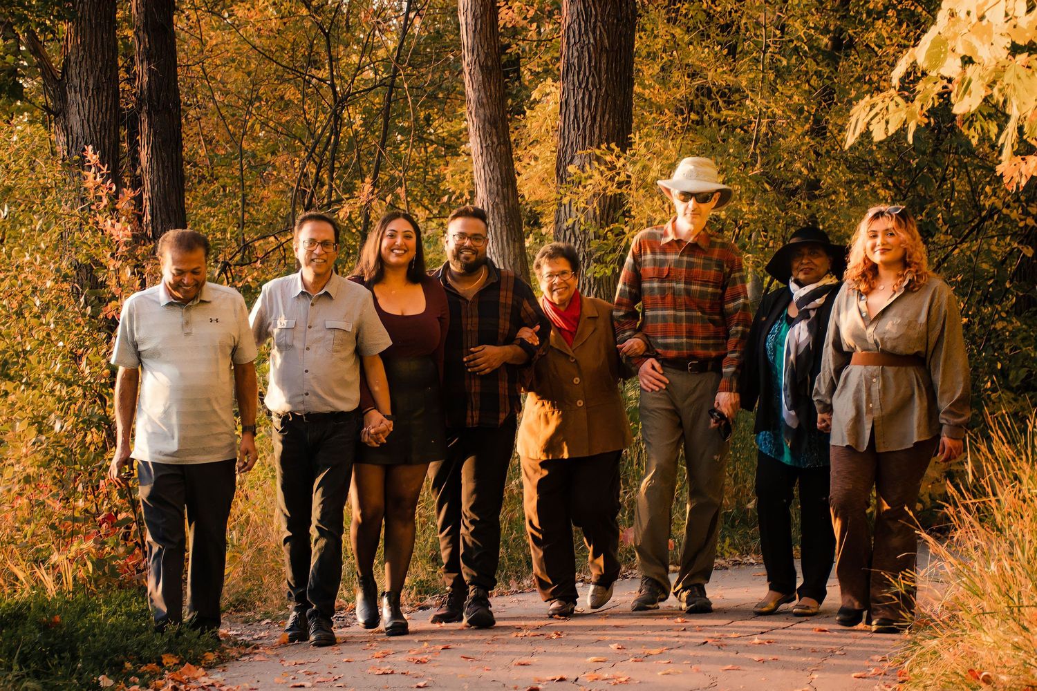 Large multigenerational family group walking together on an autumn path surrounded by colorful foliage in Winnipeg