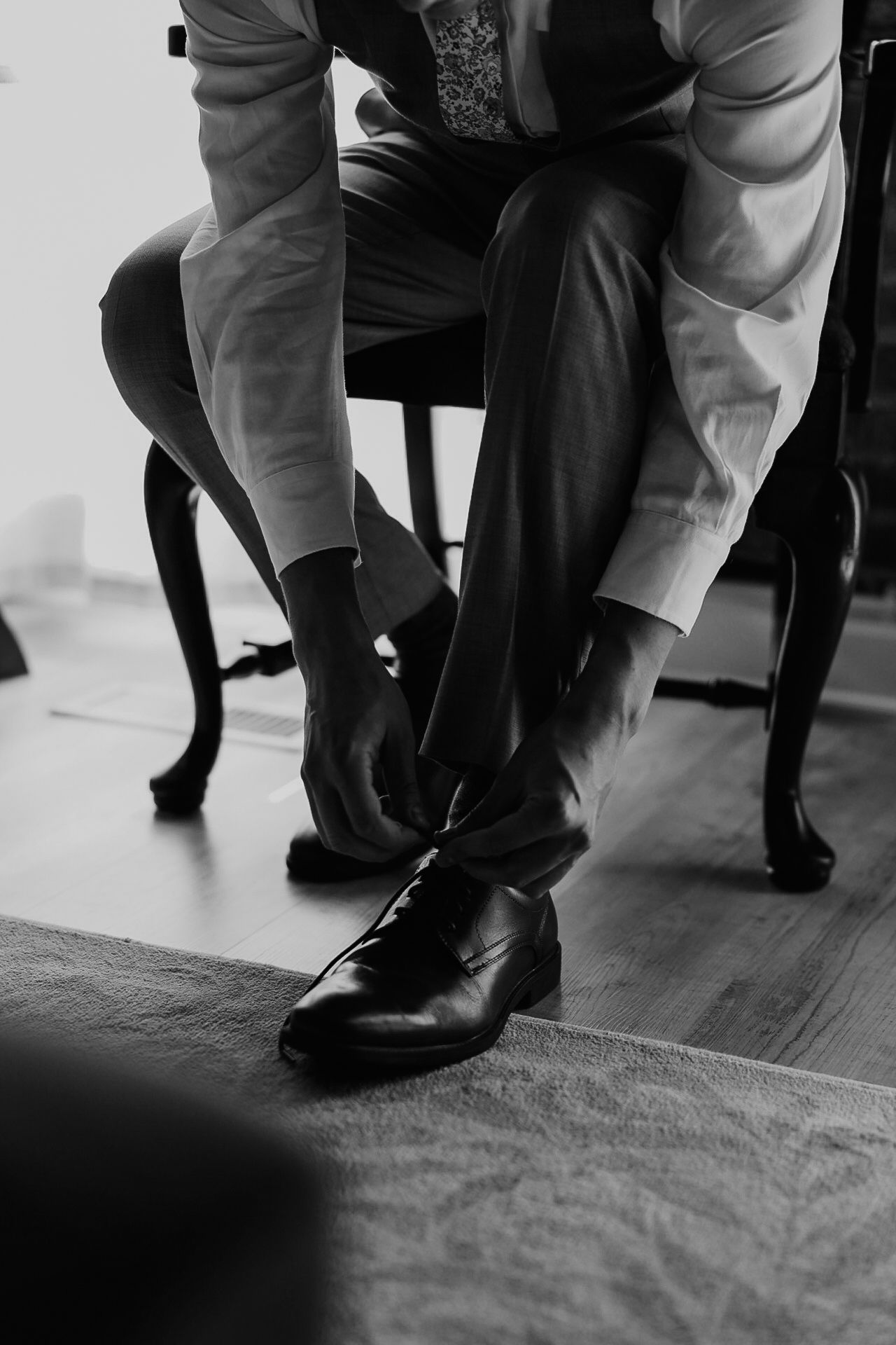 Close-up shots of formal black dress shoes being put on against a hardwood floor.