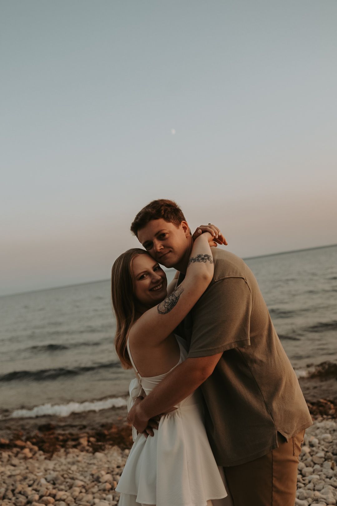 A romantic beach photoshoot at sunset with waves crashing in the background.