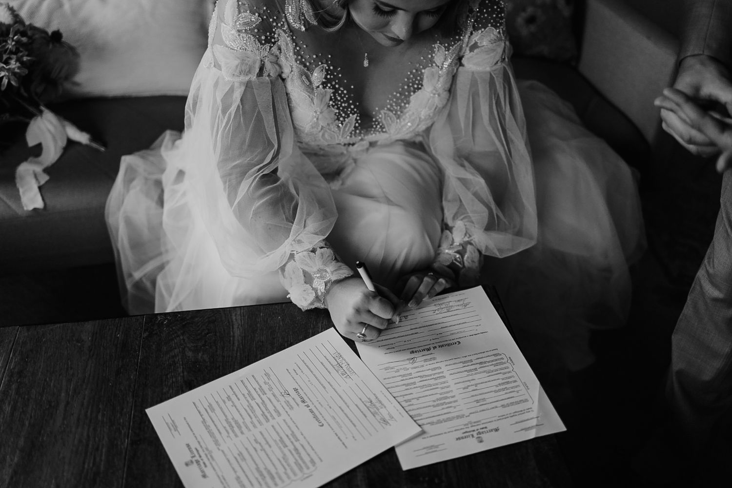 Intimate document signing moment captured in moody black and white photography.