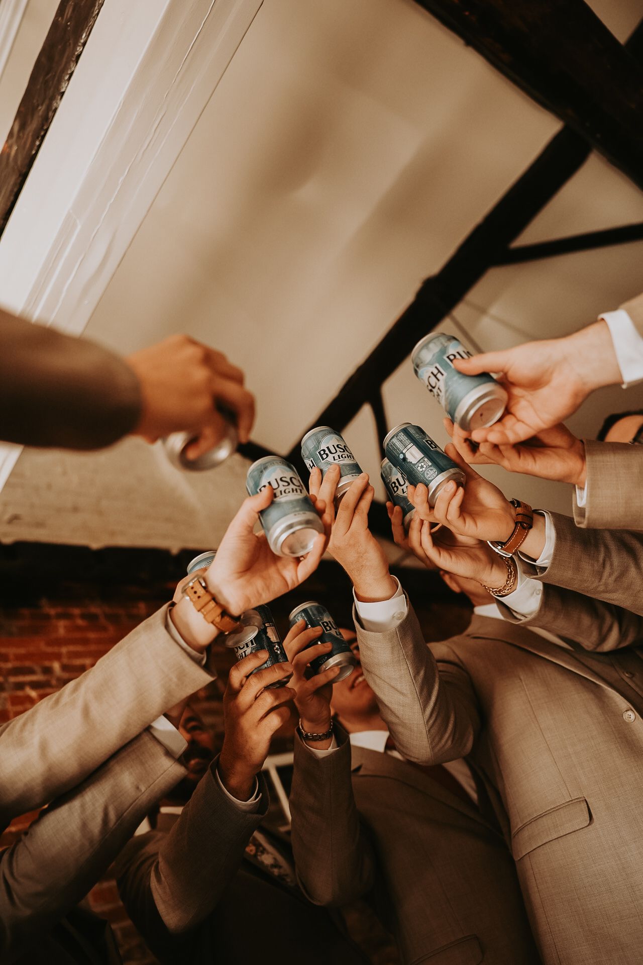 Group of hands holding beer cans together in a celebratory toast.