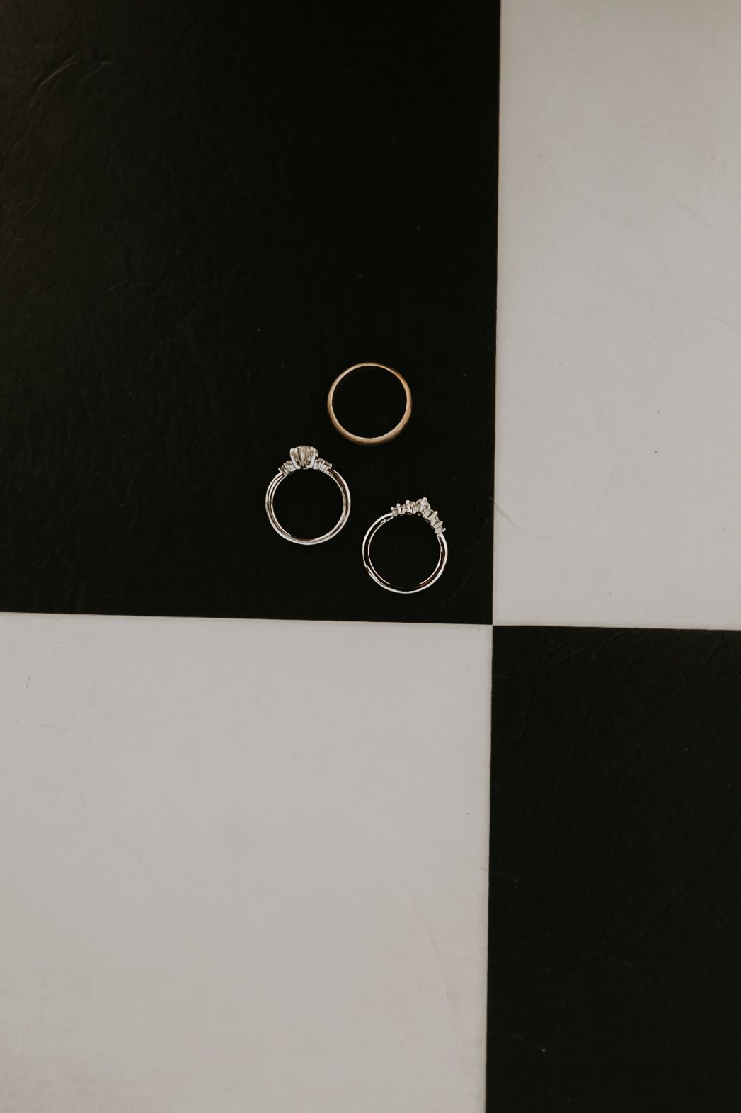 Wedding rings arranged on a black and white checkered background.