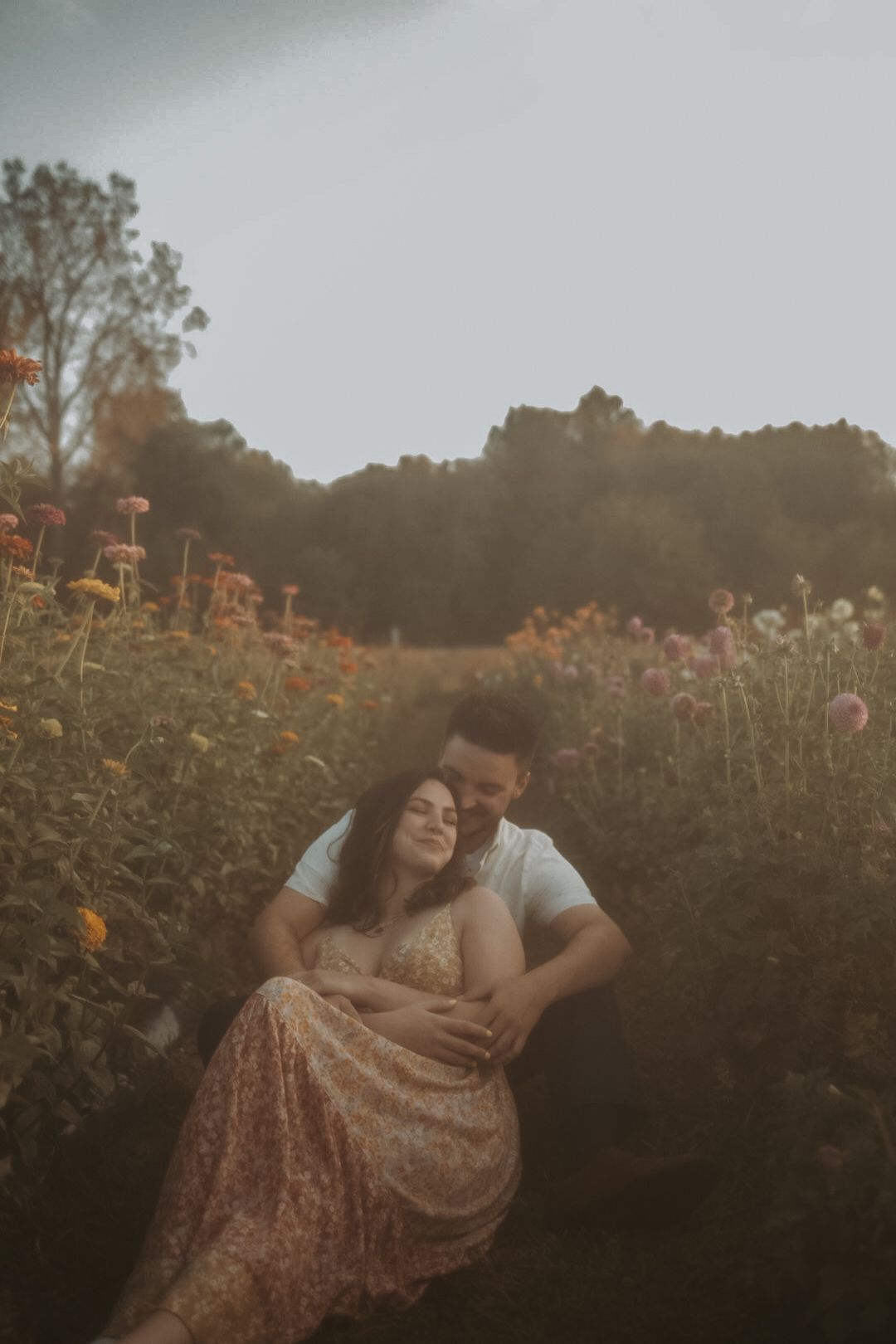 Romantic couple embracing in a wildflower meadow at dusk.