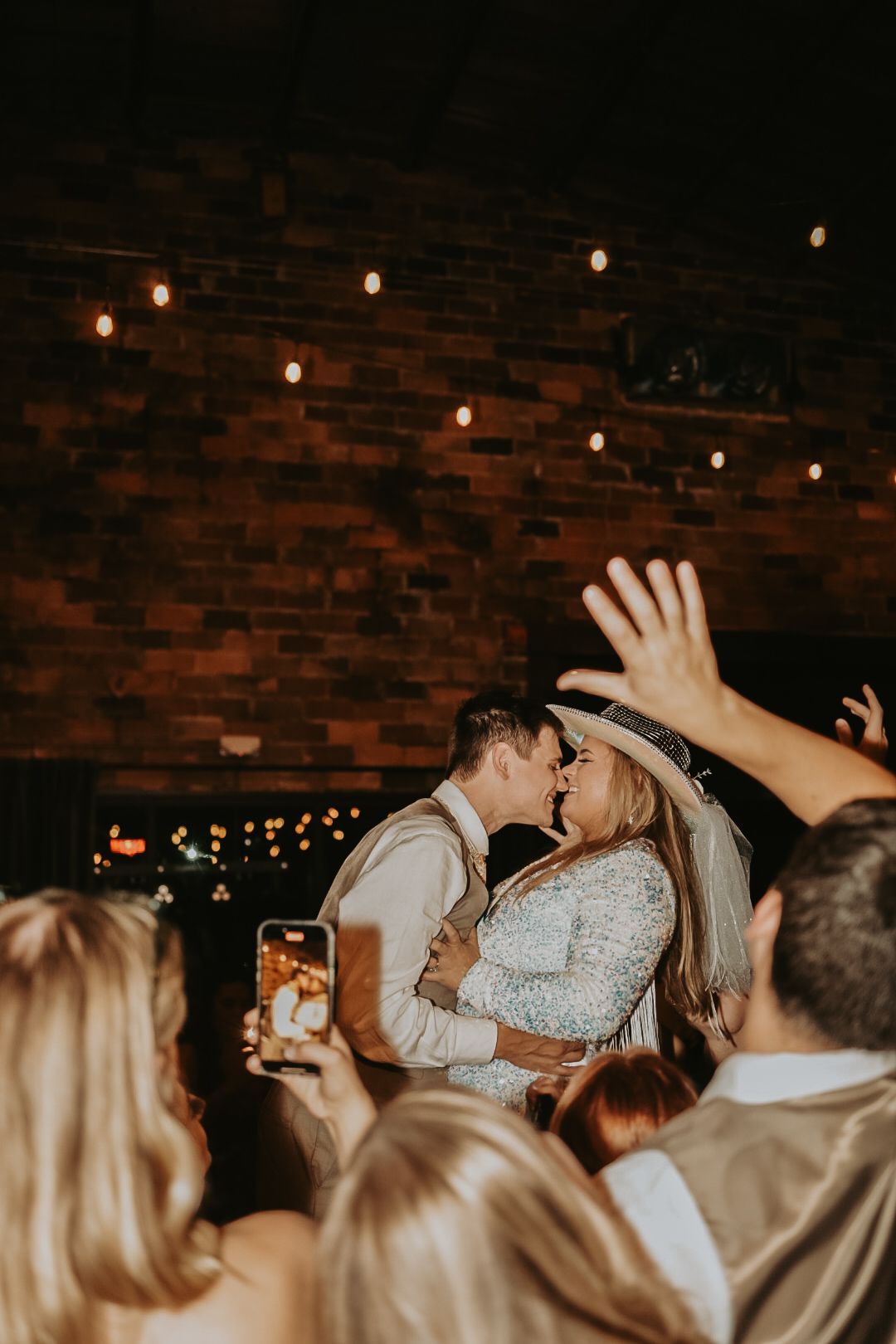 Festive celebration moment at indoor venue with brick walls and string lights.