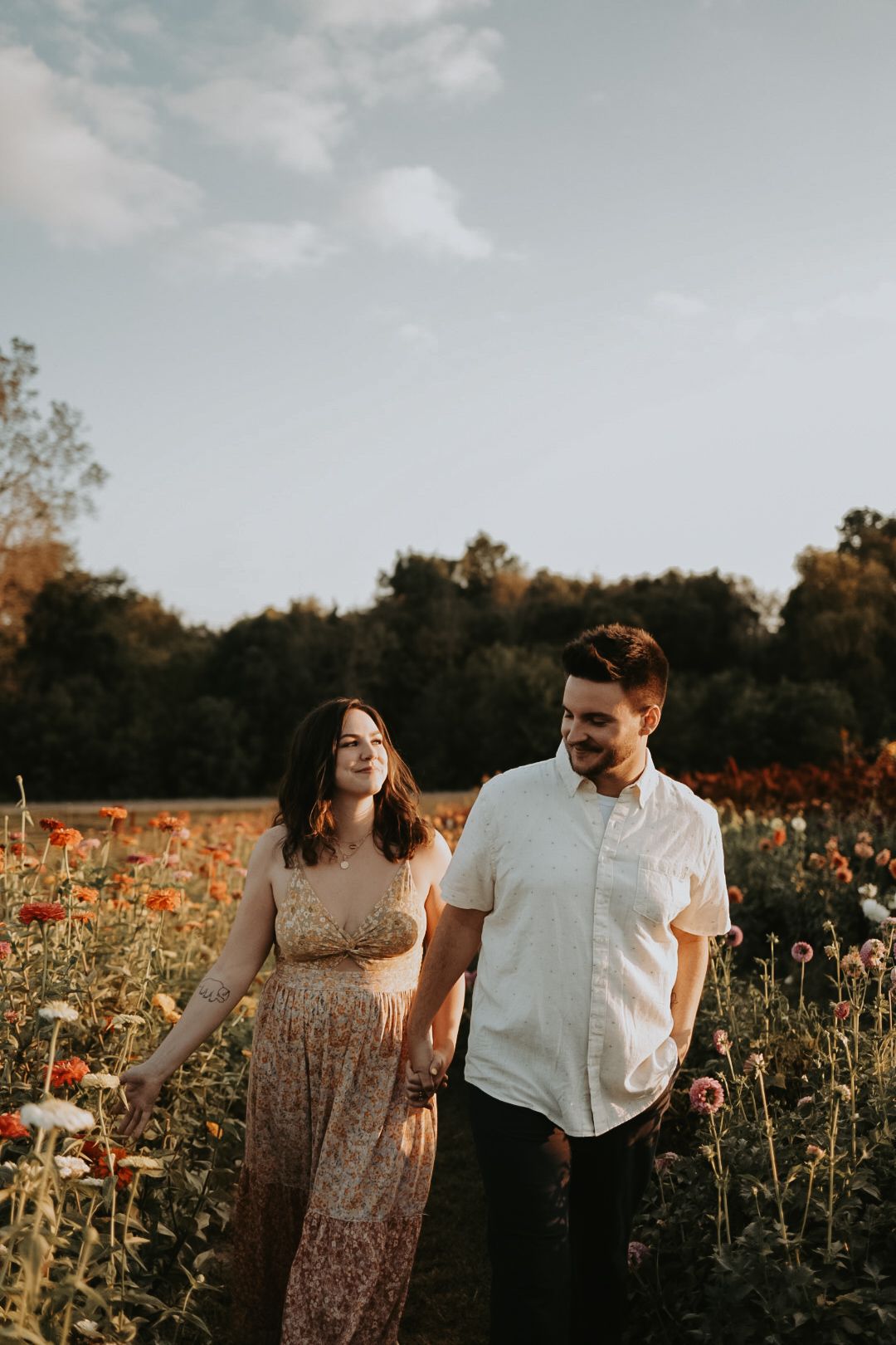 A couple poses together in a vibrant field of orange wildflowers.