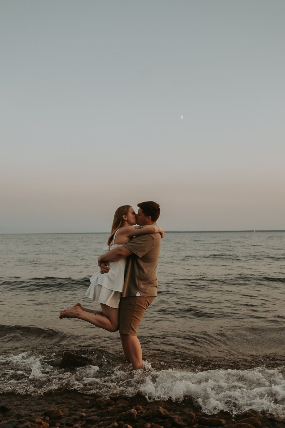 A joyful embrace by the ocean with waves splashing in the background.