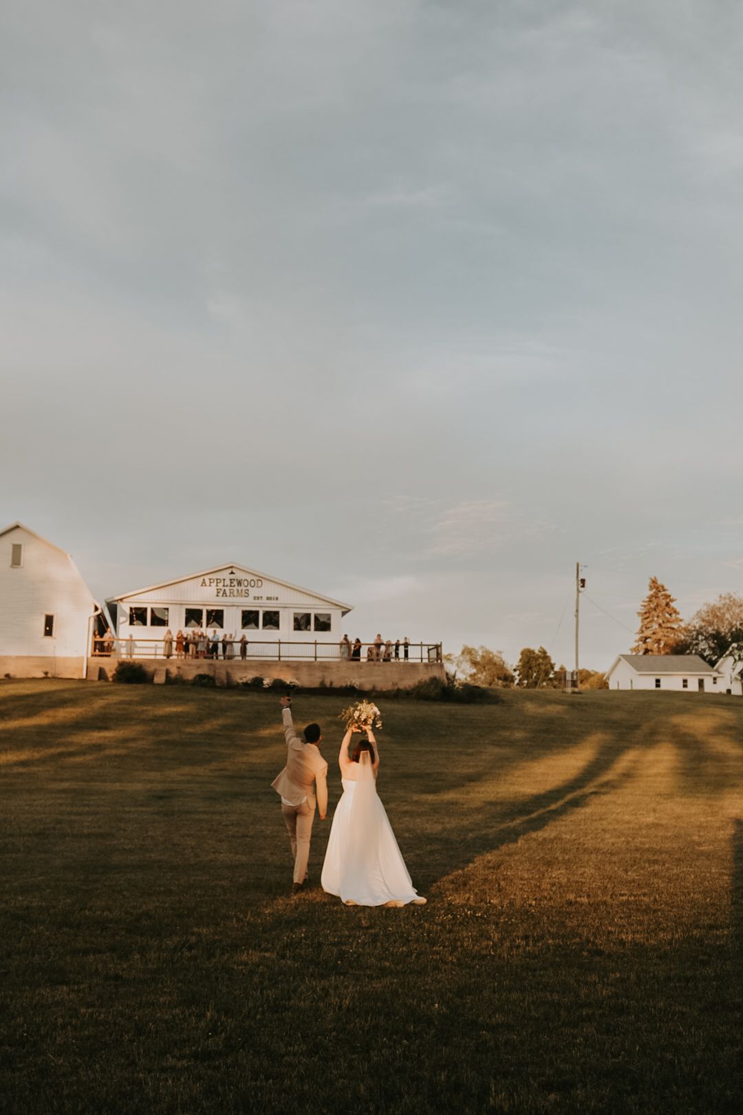 Wedding couple silhouetted against a hilltop venue during golden hour.