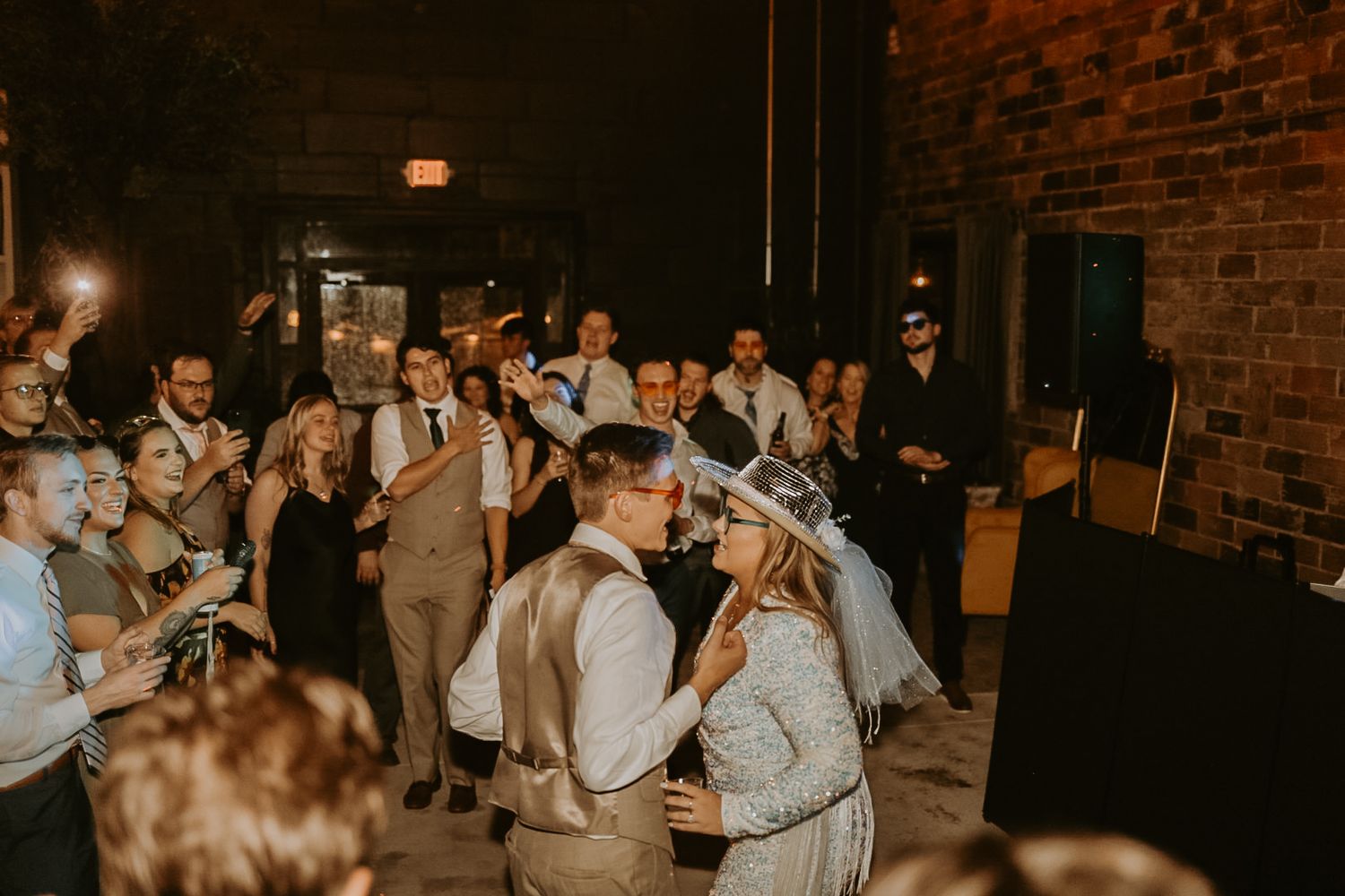 Guests celebrating on the dance floor at an indoor wedding reception.