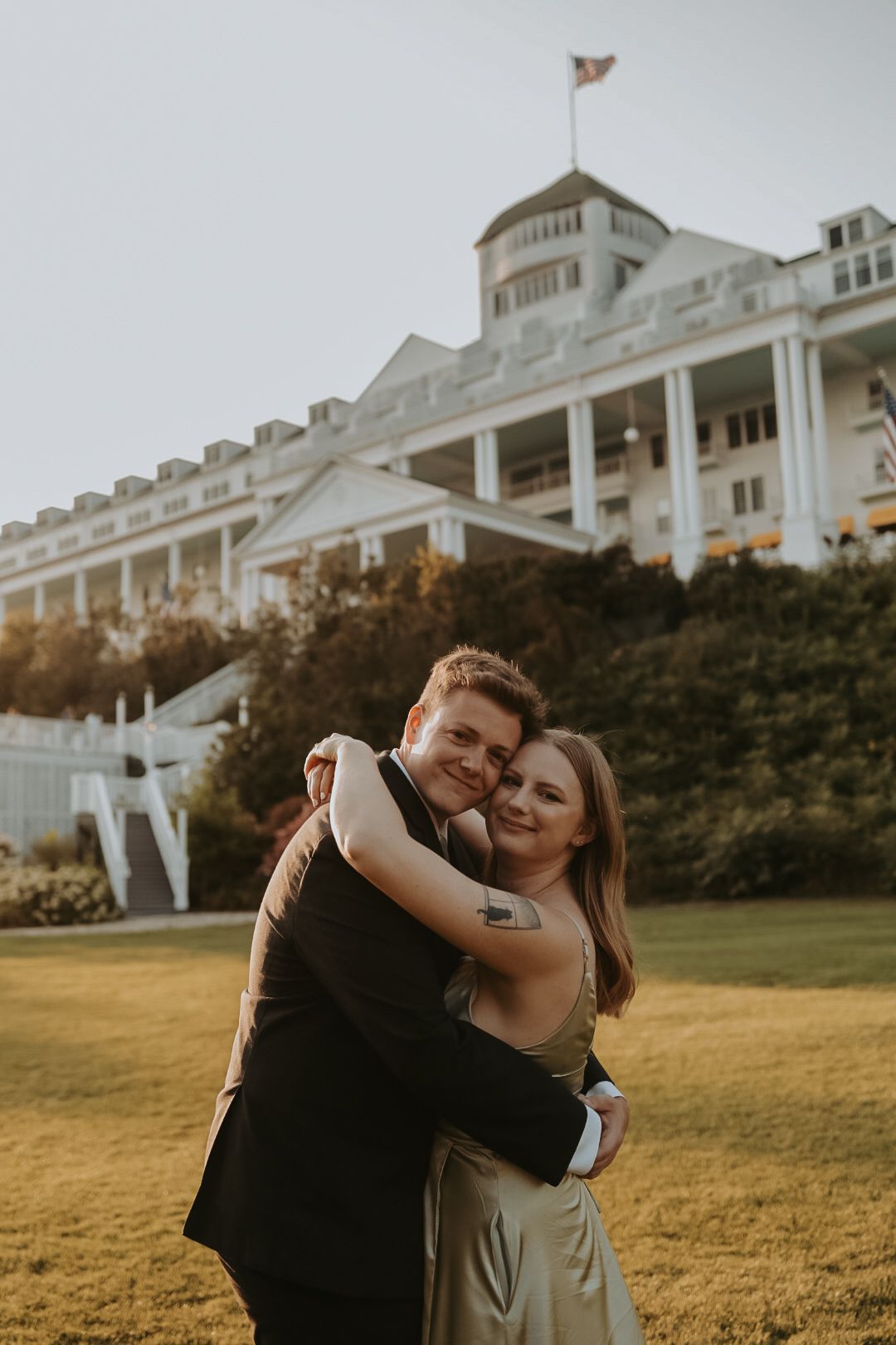 A romantic sunset photoshoot in front of a grand white hotel building with golden hour lighting.