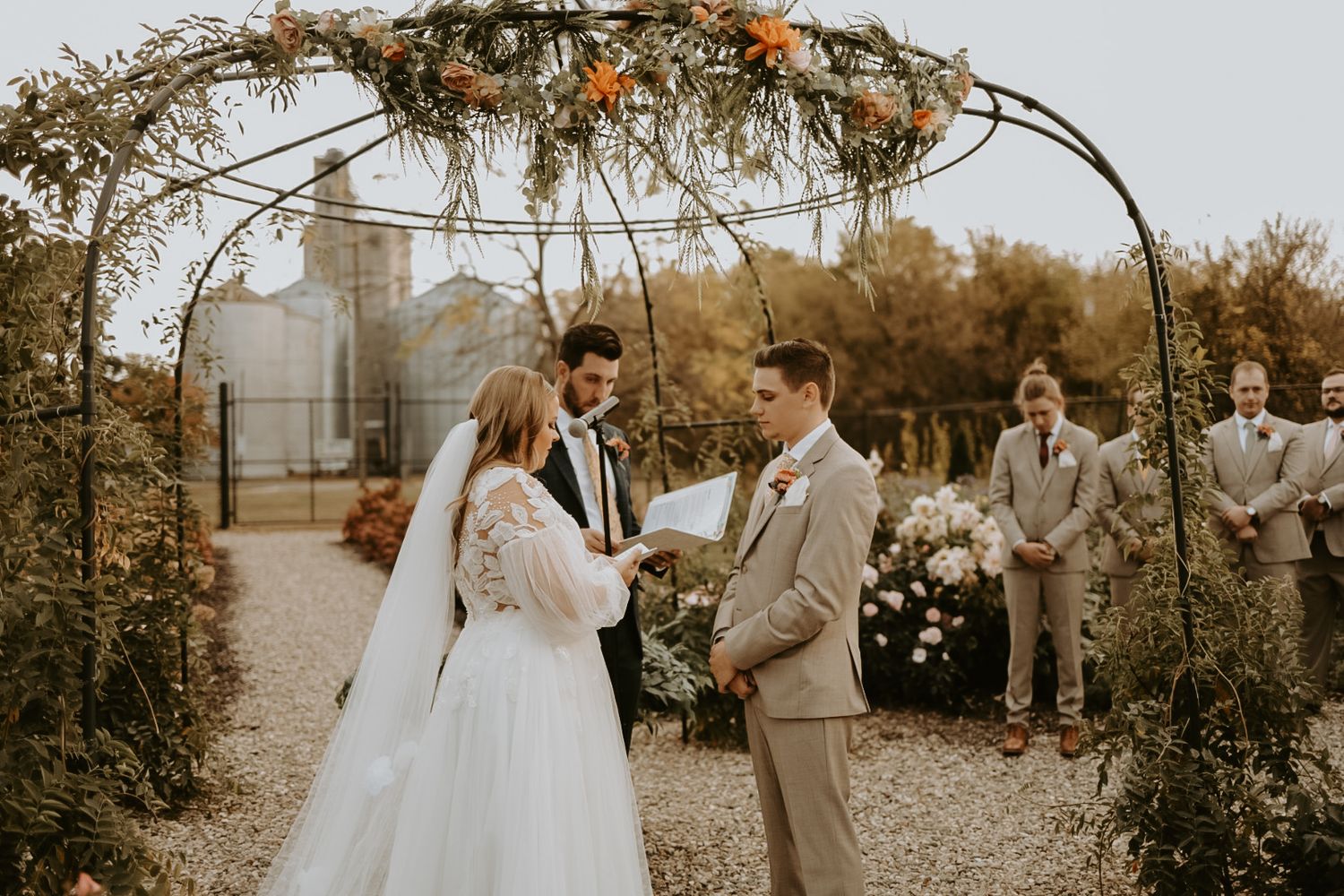 Wedding ceremony setup with natural arch and autumn decorations in an outdoor garden setting.