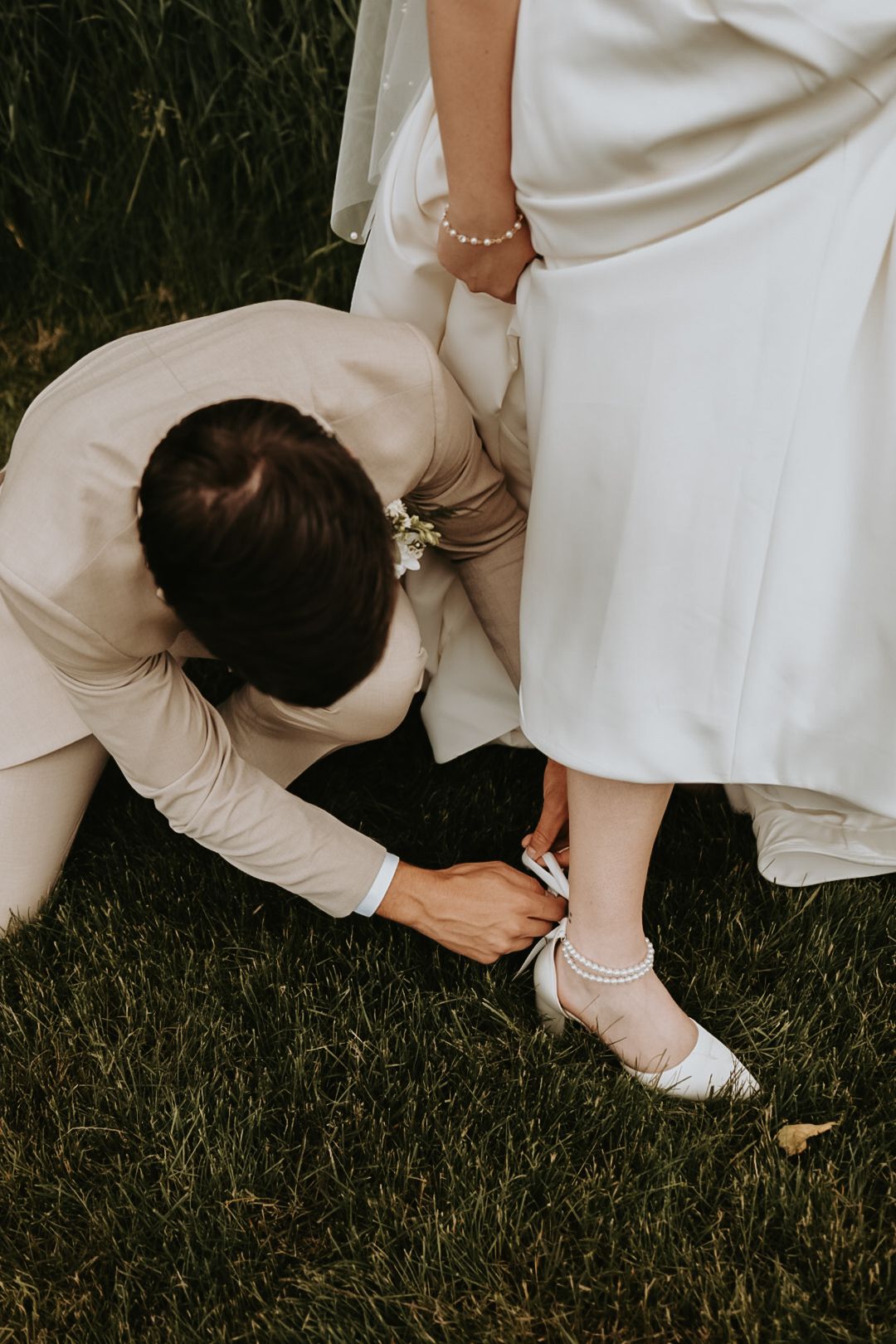 Close-up of wedding shoe being adjusted on grass during preparation.