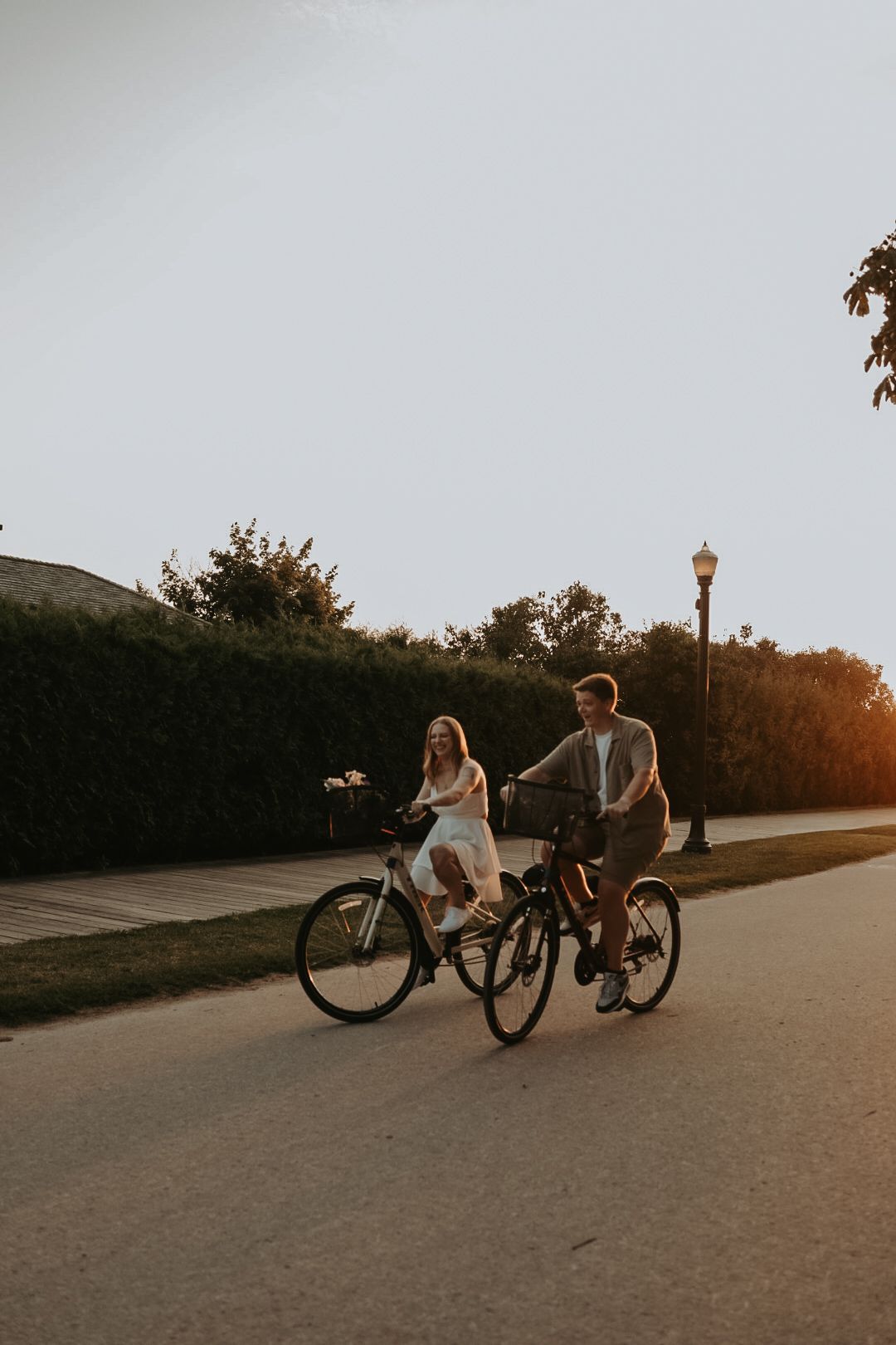 Couple relaxes with their bikes on path during golden hour photoshoot.