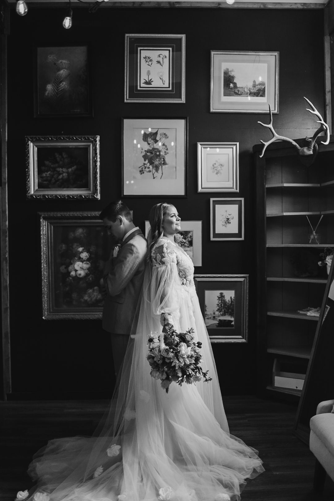 Artistic black and white wedding photo with dramatic lighting and gallery wall setting.