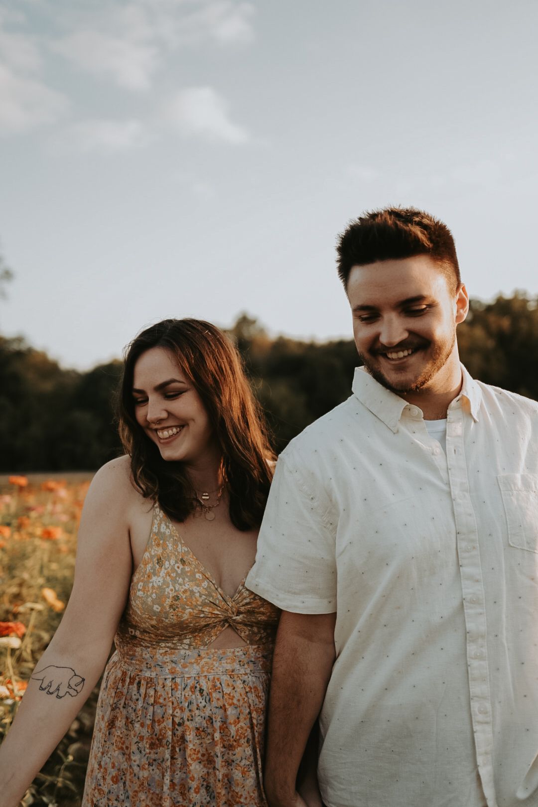 Couple sharing a joyful moment in a field of orange flowers.