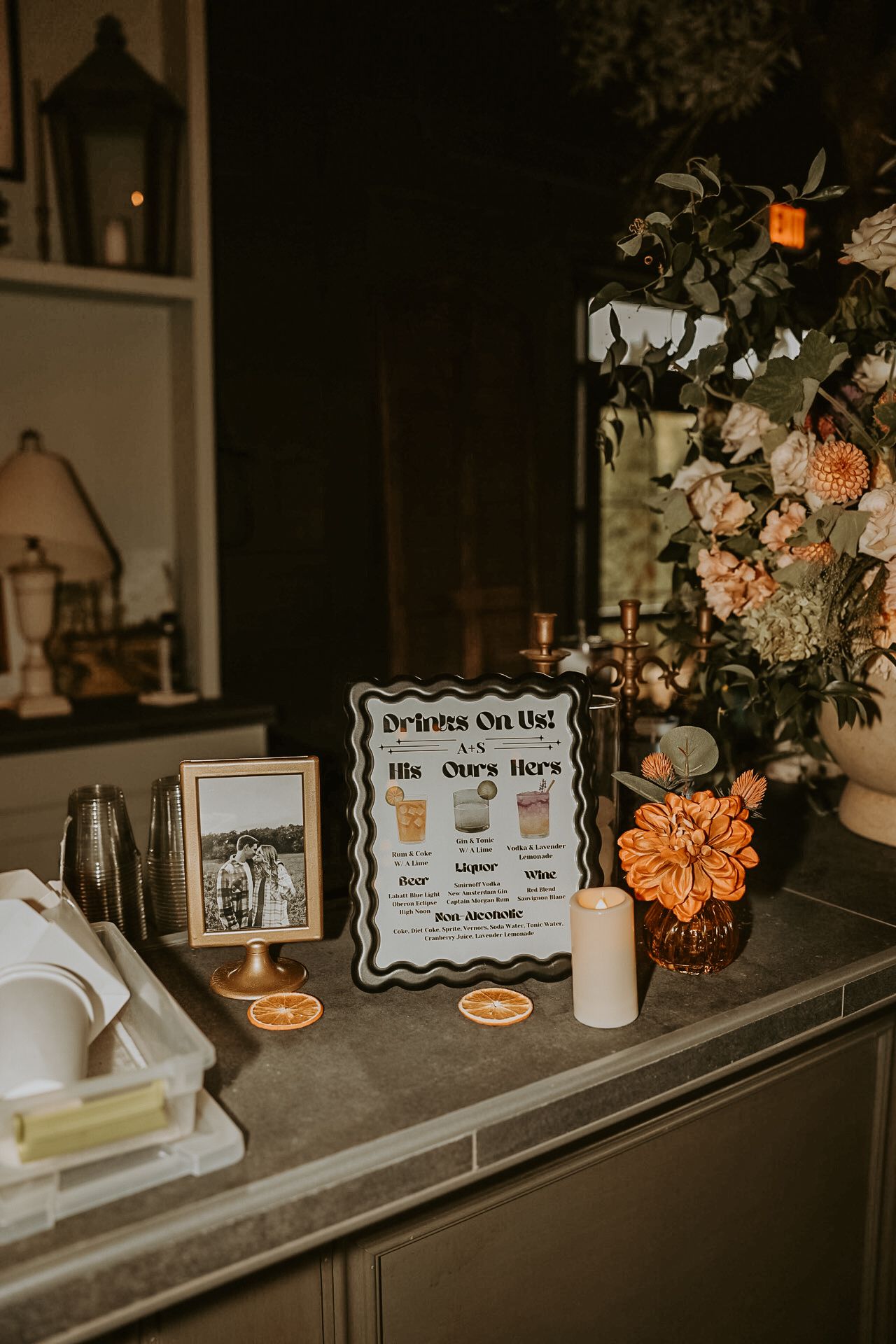 Wedding details table with vintage decor, dried flowers, and framed signage.
