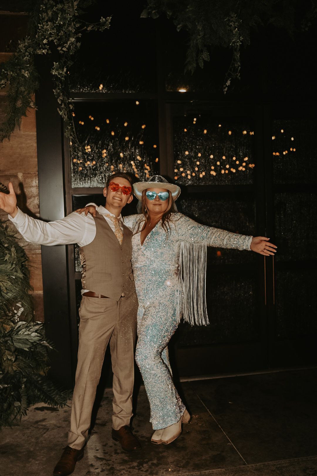 Wedding guests dancing and posing in formal attire at an evening reception.
